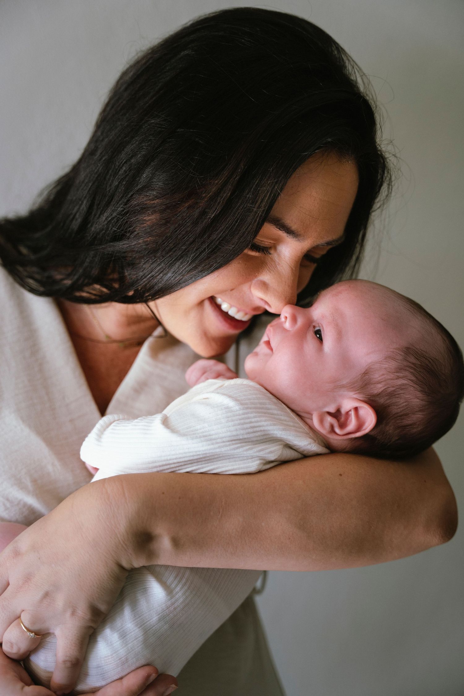 Mother cradling her newborn during a cozy, intimate newborn shoot in Curaçao. / Moeder en pasgeboren baby tijdens photoshoot op Curacao.