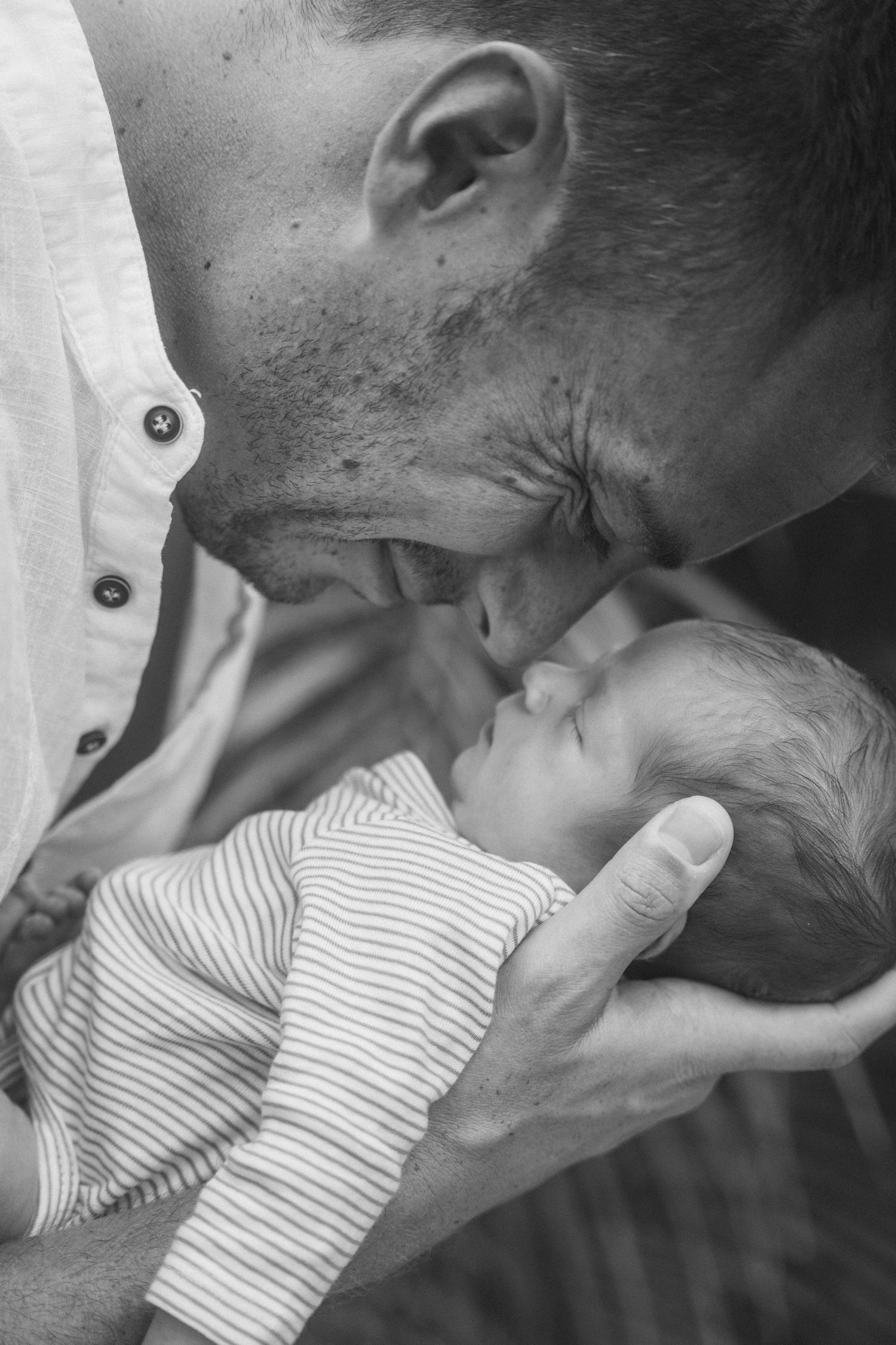 Father holds newborn during a natural light family session in Curaçao. / Papa houdt pasgeboren baby vast tijdens een fotoshoot Curacao.