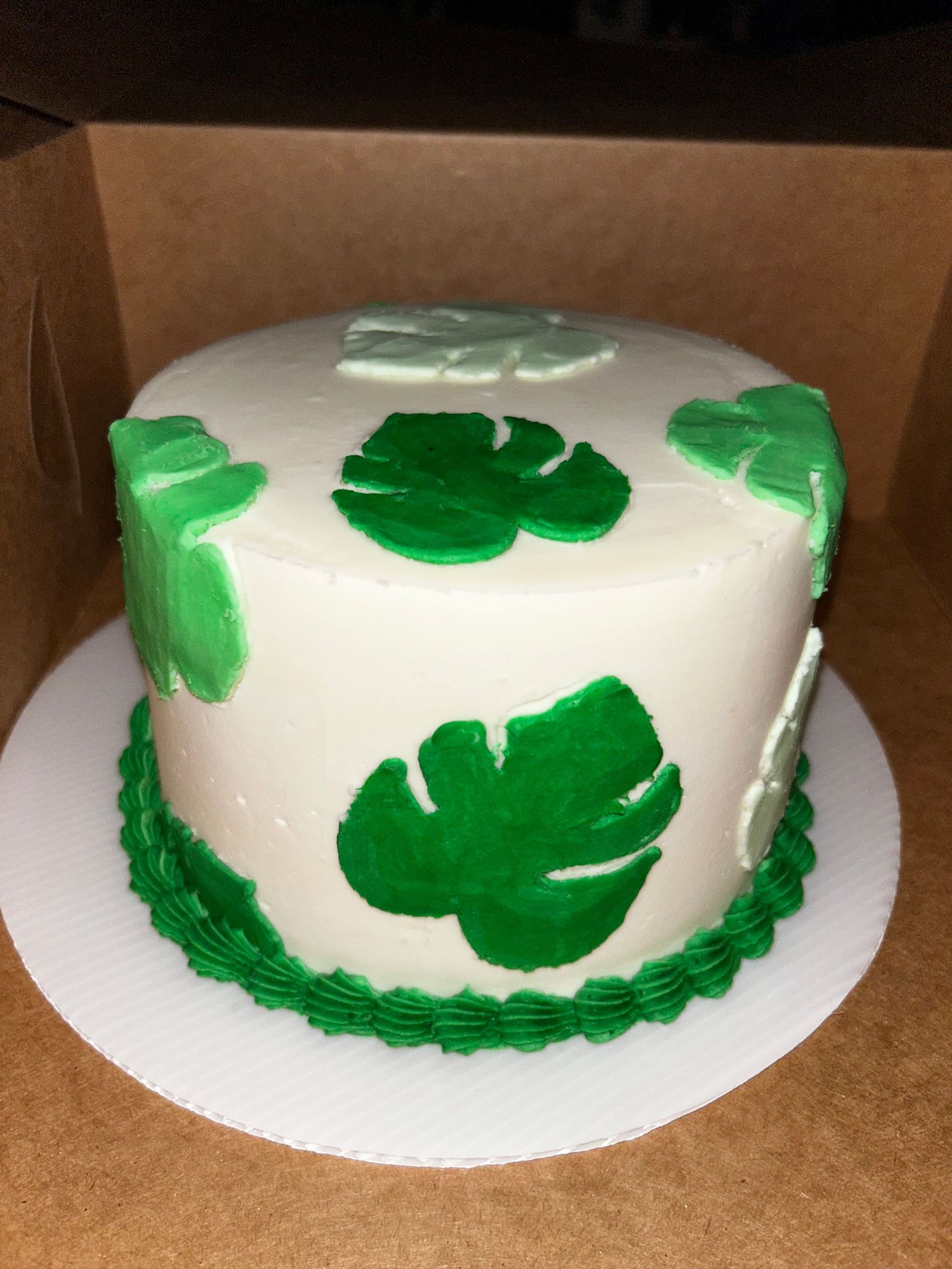 White round cake decorated with green shamrock patterns around the sides.