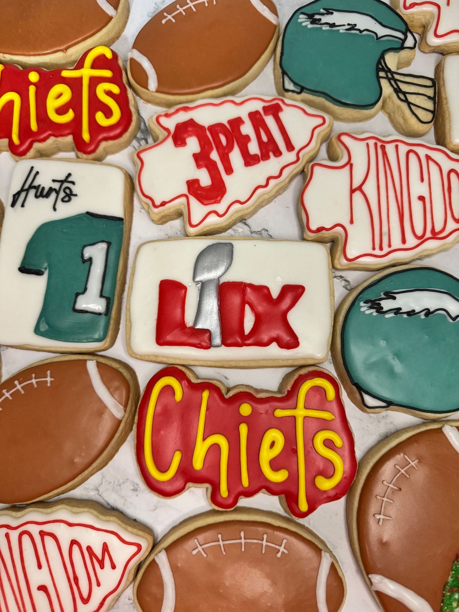 Sports-themed decorated cookies featuring football helmets and team logos in teal and brown colors.