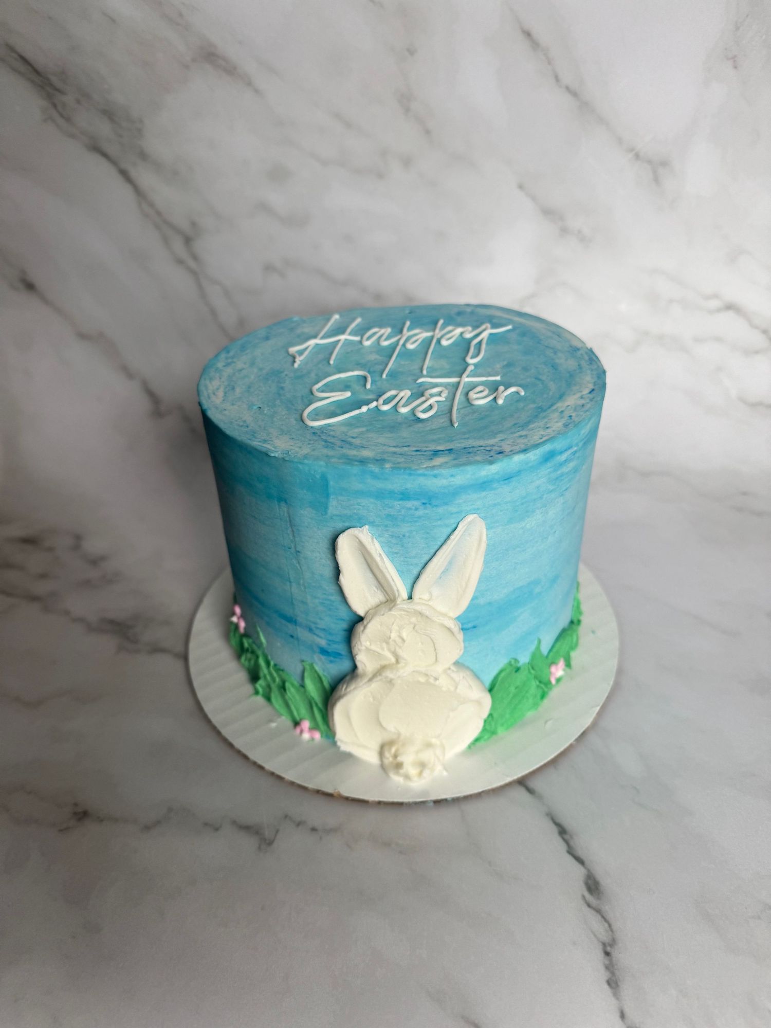 Easter-themed cake with blue frosting and white bunny silhouette decoration.