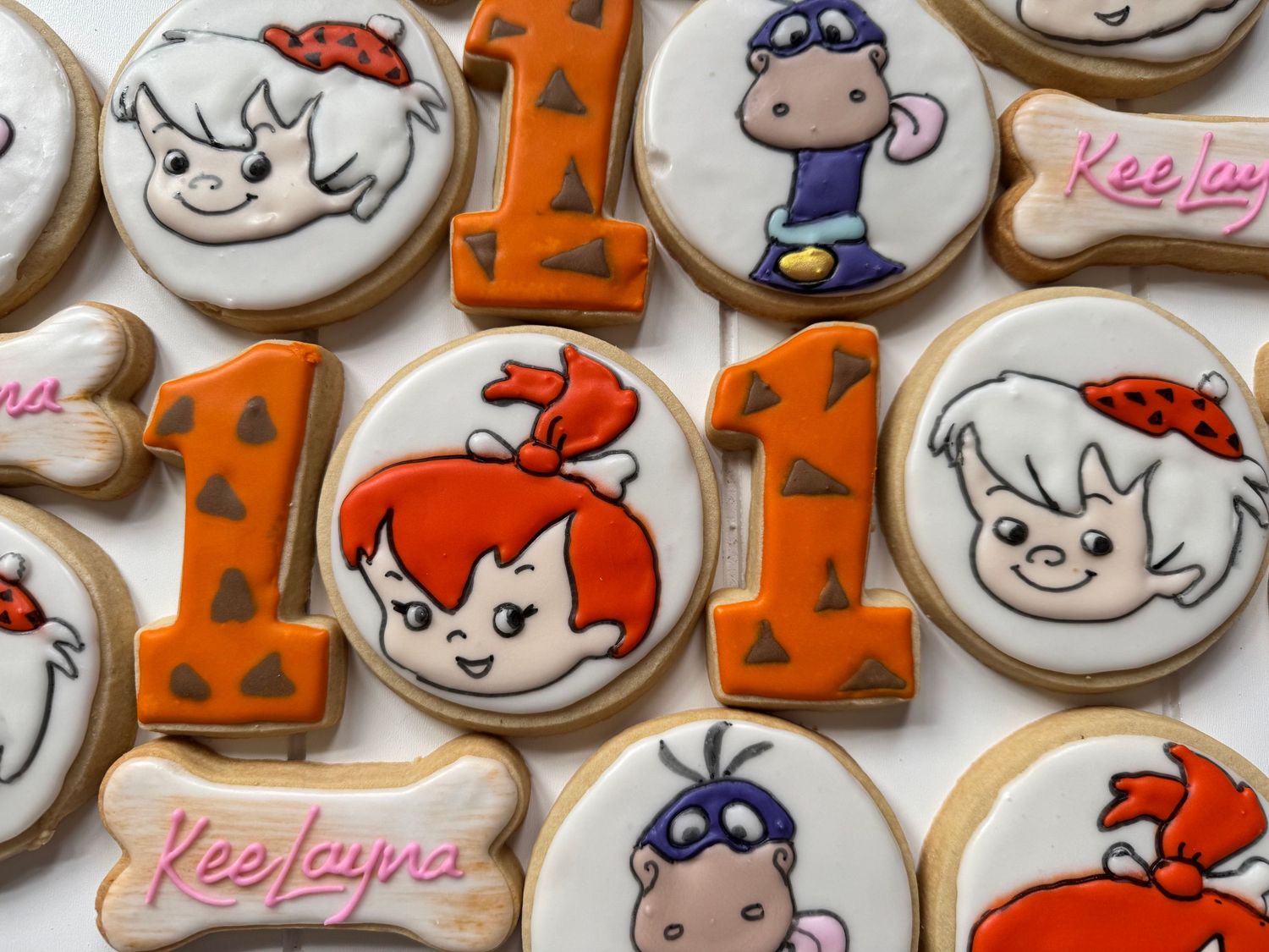 Collection of cartoon character themed sugar cookies with orange and red decorative details.