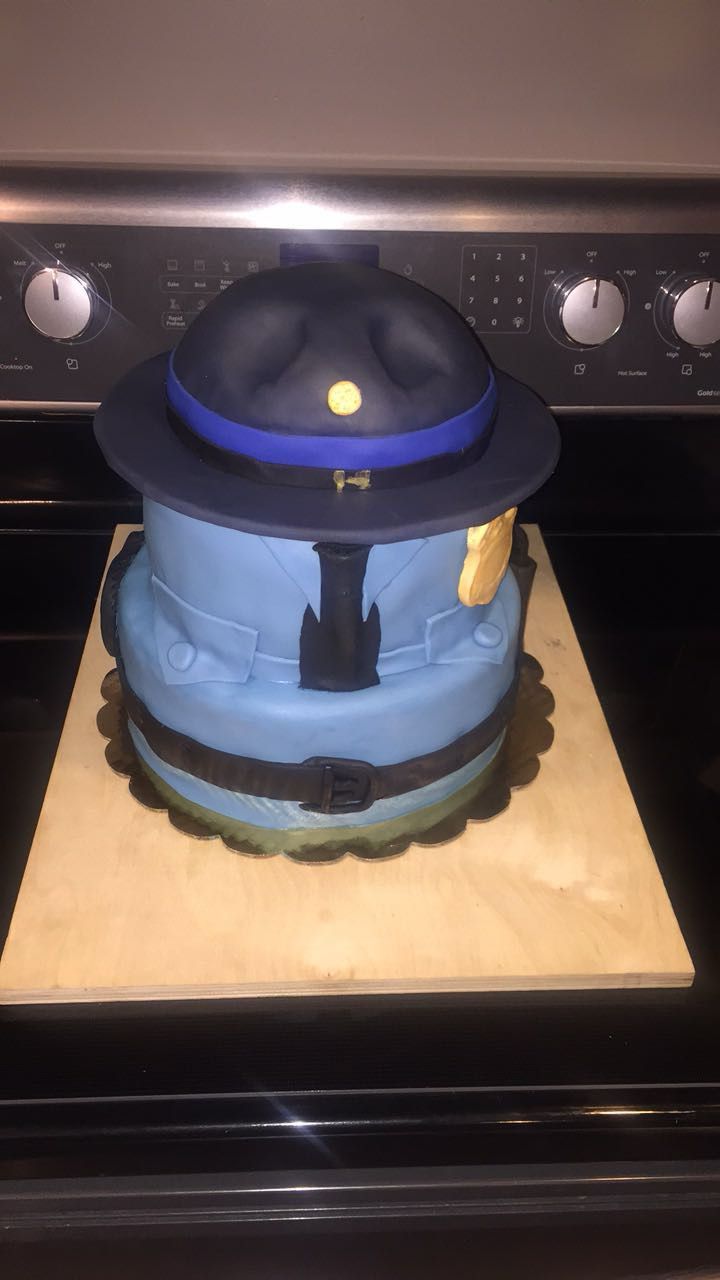 Police officer themed cake shaped like a uniform hat with blue frosting and black details.