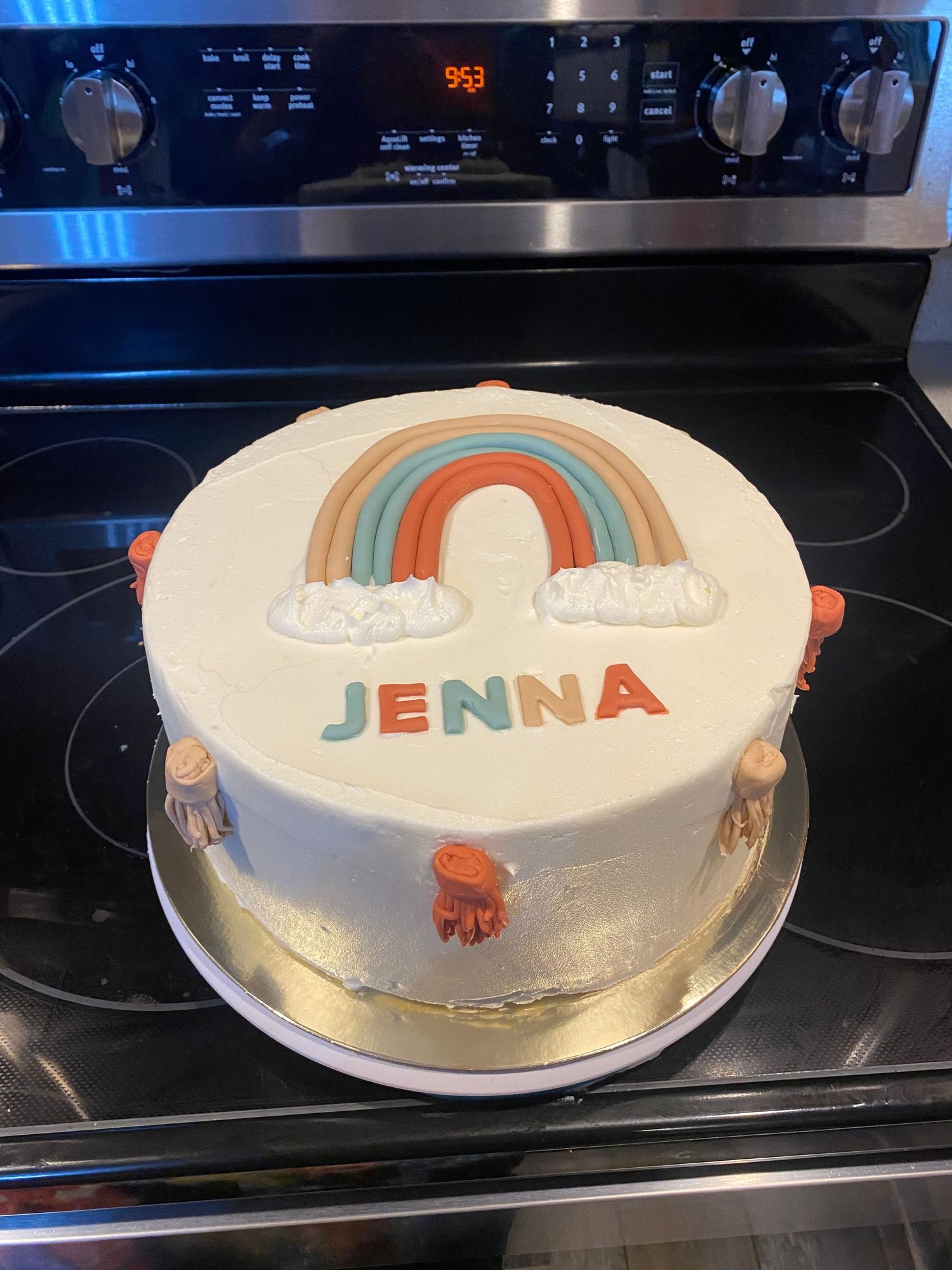 White round cake decorated with retro-style rainbow stripes and text in teal and orange.