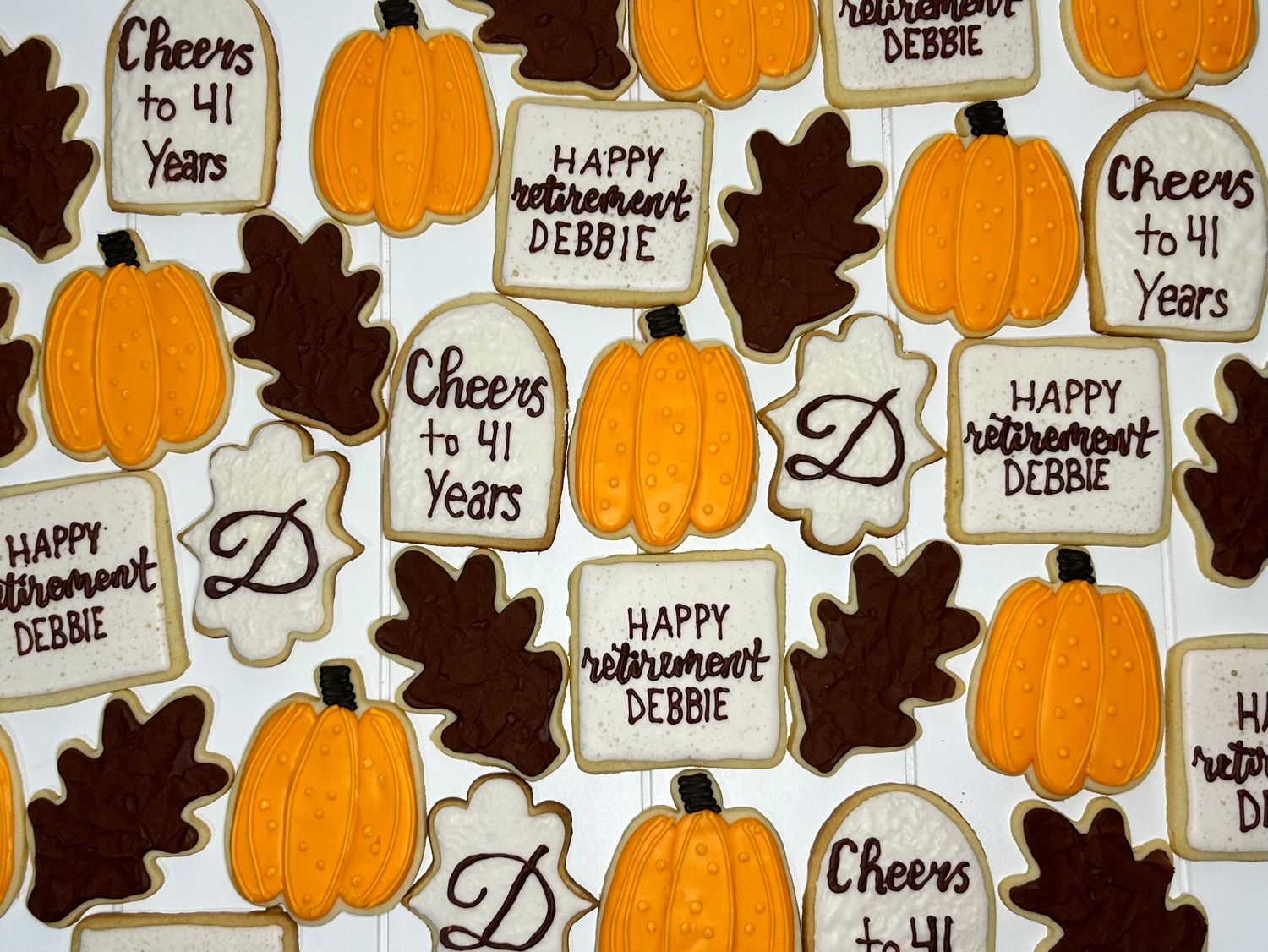 Fall-themed sugar cookies decorated with orange pumpkins and brown leaves with text messages.