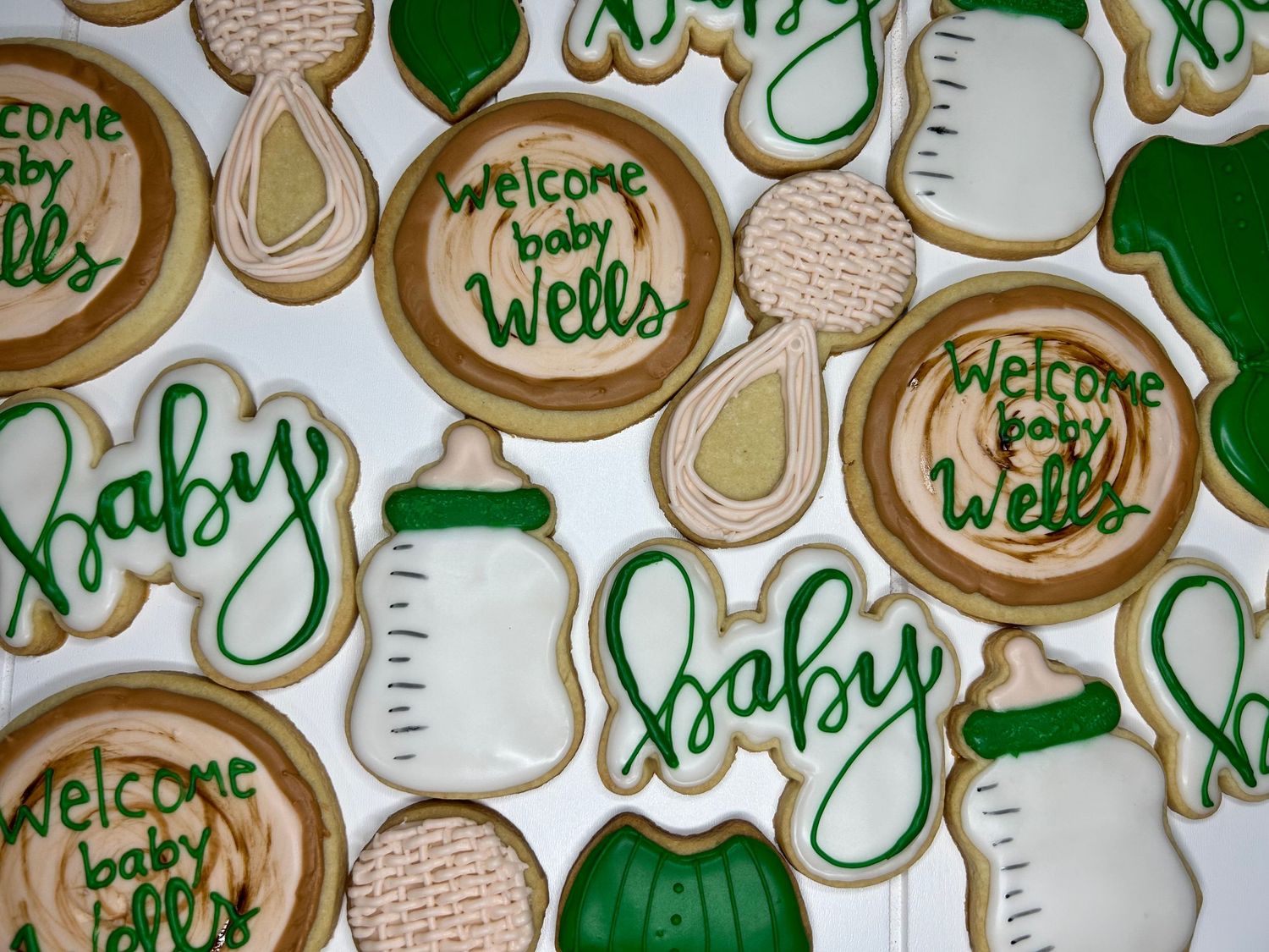 Sugar cookies decorated with green baby-themed designs and welcome messages.