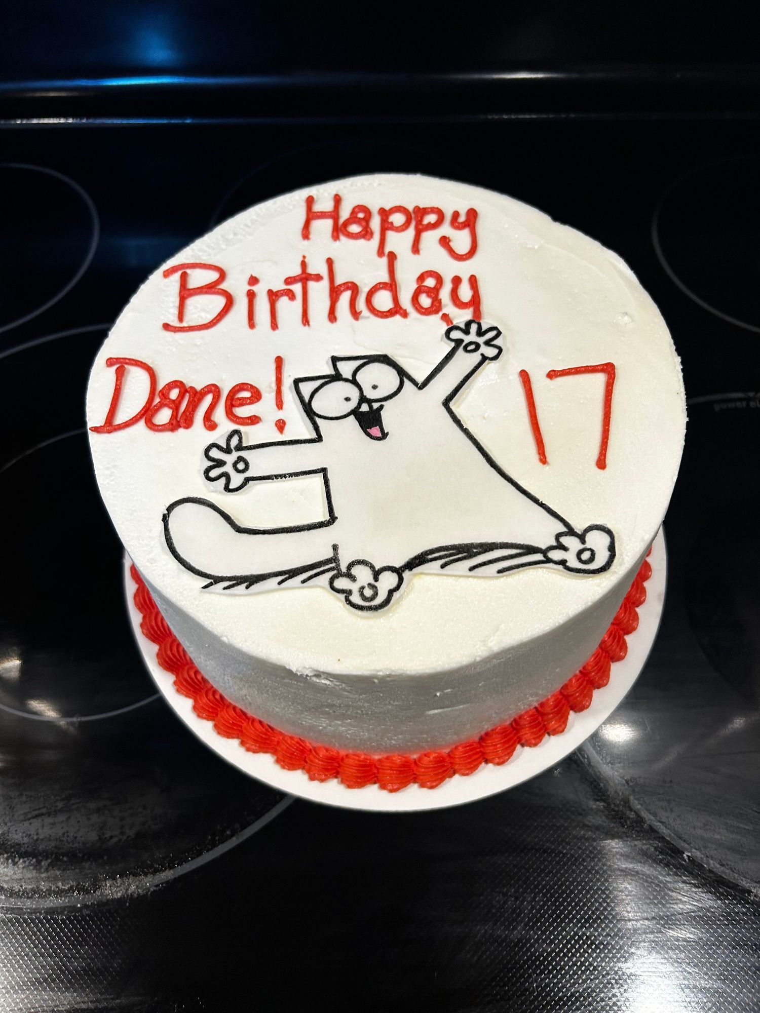 A simple white frosted cake with red trim and a helicopter sketch design.