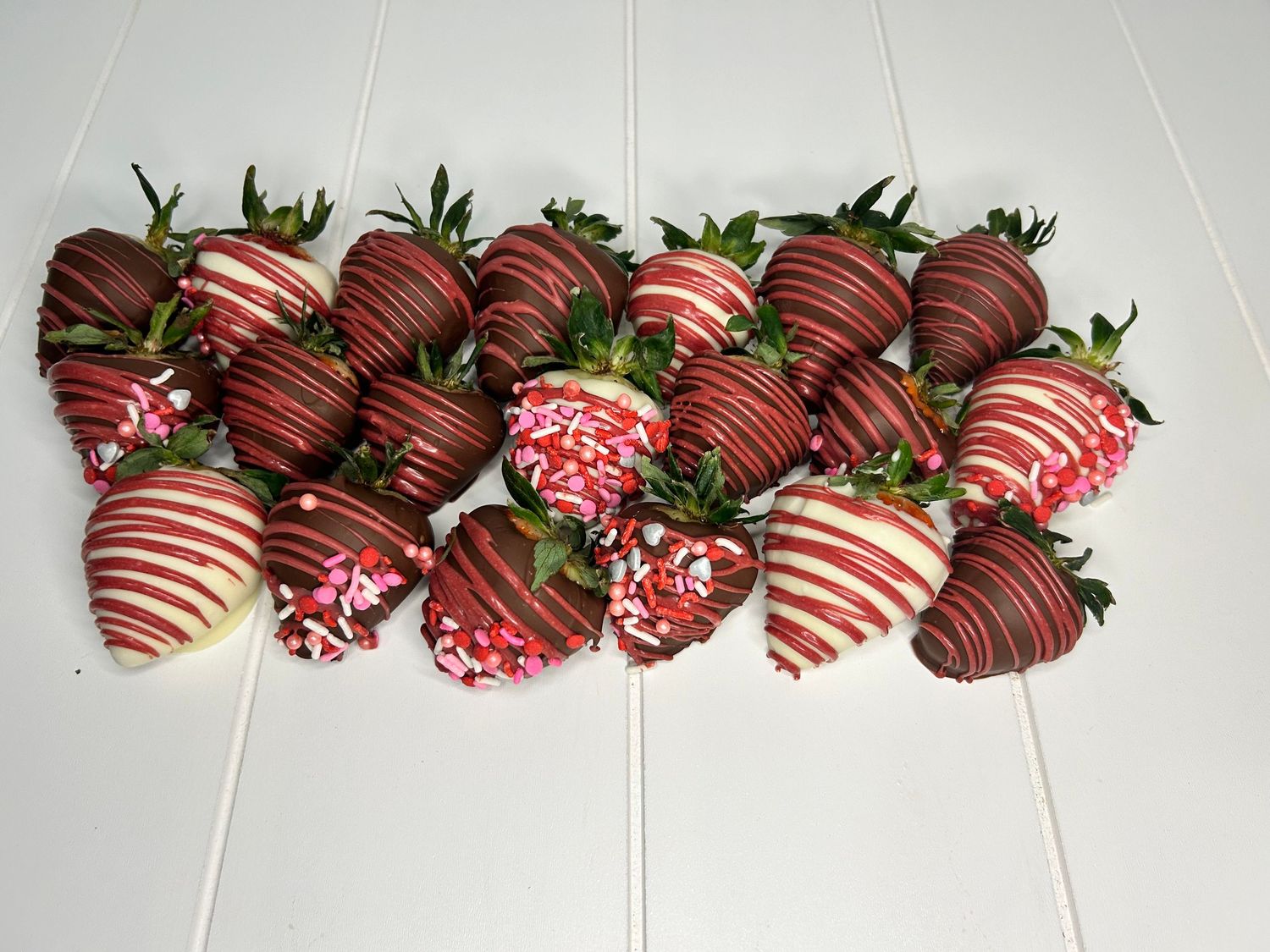 Chocolate covered strawberries decorated with pink and white stripes and sprinkles.