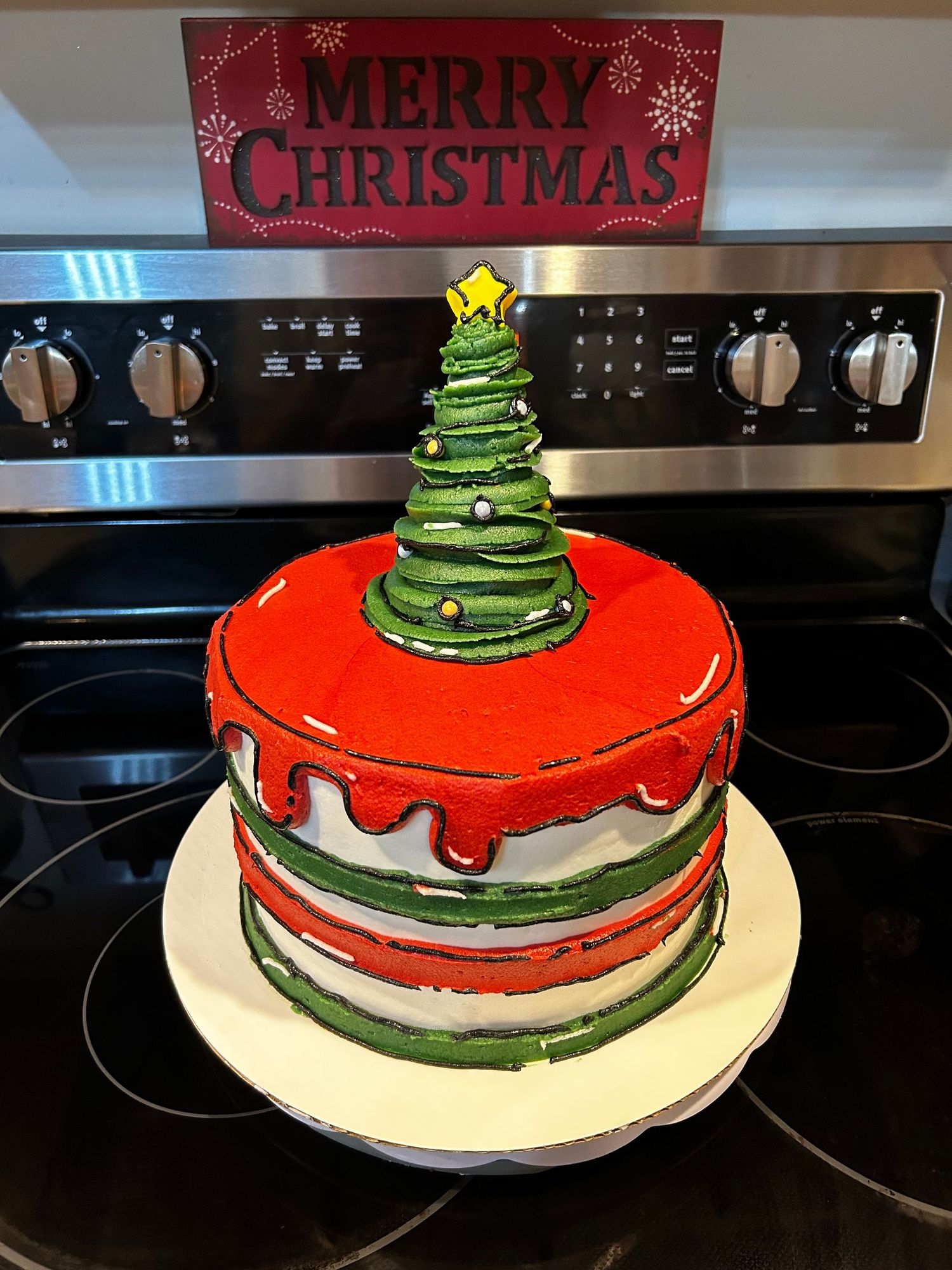 A Christmas-themed cake decorated with red frosting and a green Christmas tree topper on a white plate.