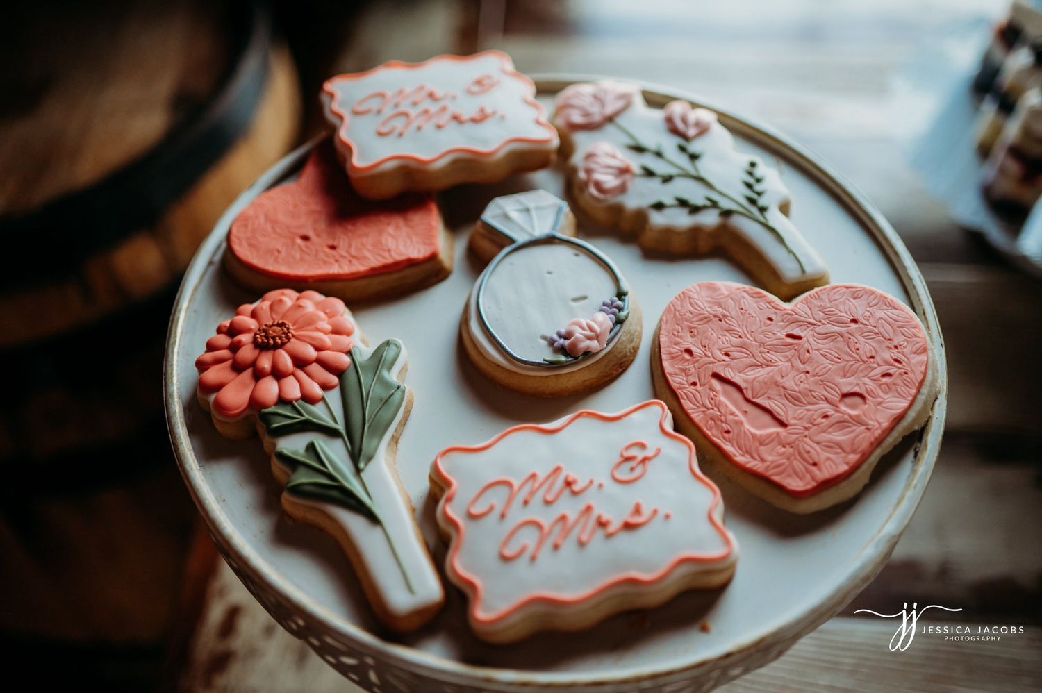 Artistically decorated valentine cookies with coral pink frosting on white serving plate.