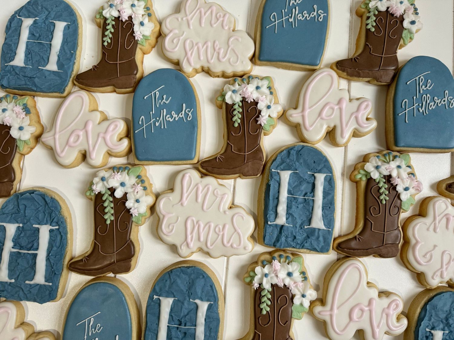 Decorative sugar cookies with blue mason jars, brown cowboy boots, and pink love text designs.