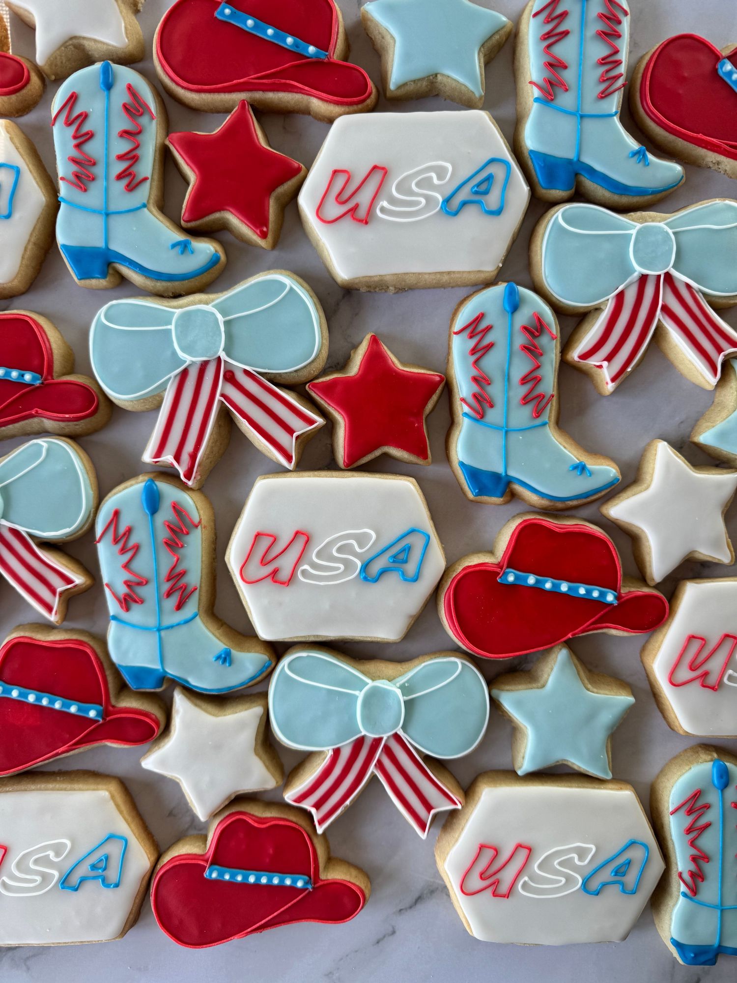 Patriotic themed sugar cookies decorated with red, white and blue icing featuring stars, bows, and USA designs.
