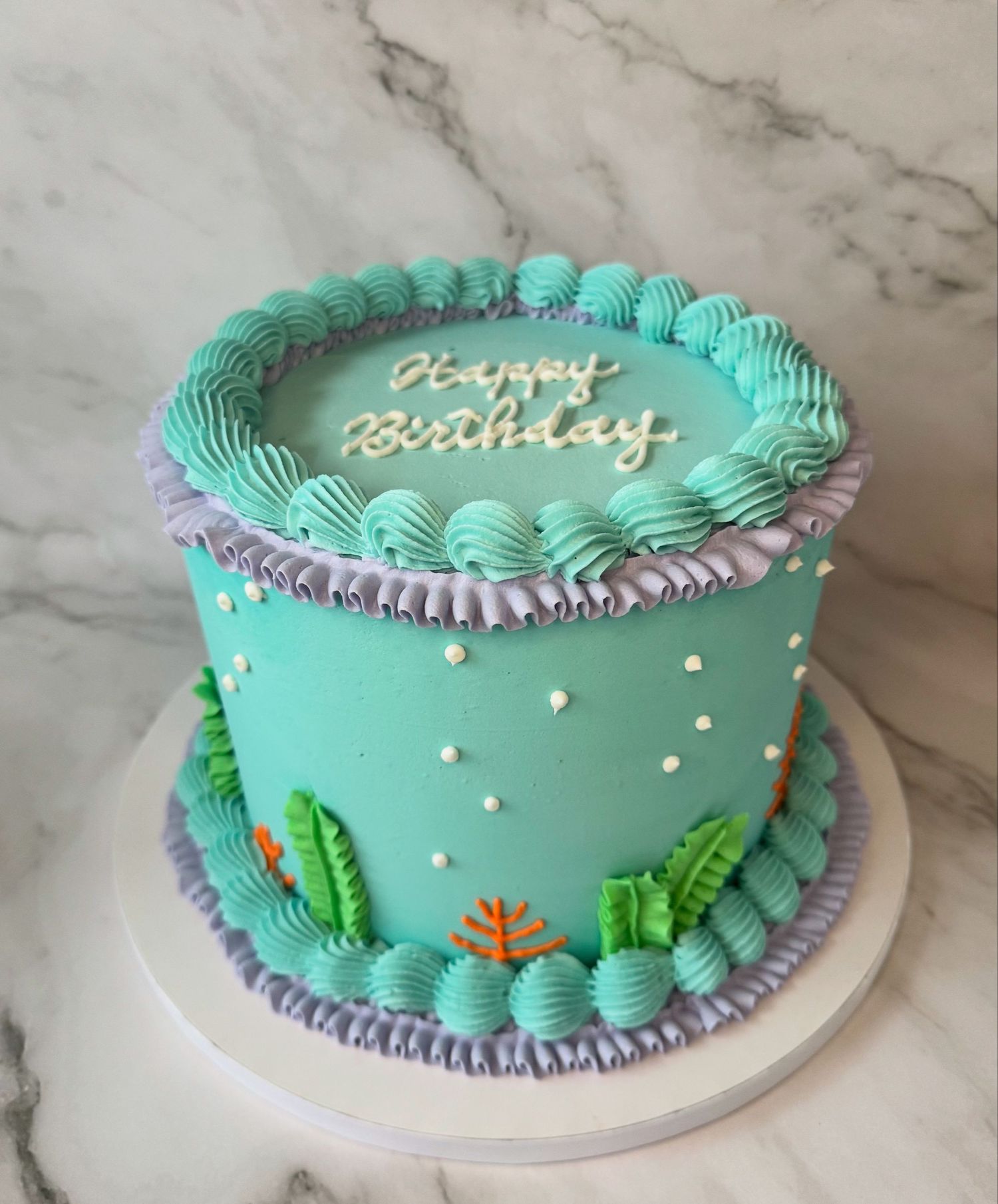 Mint green birthday cake with purple trim and decorative piped frosting details.