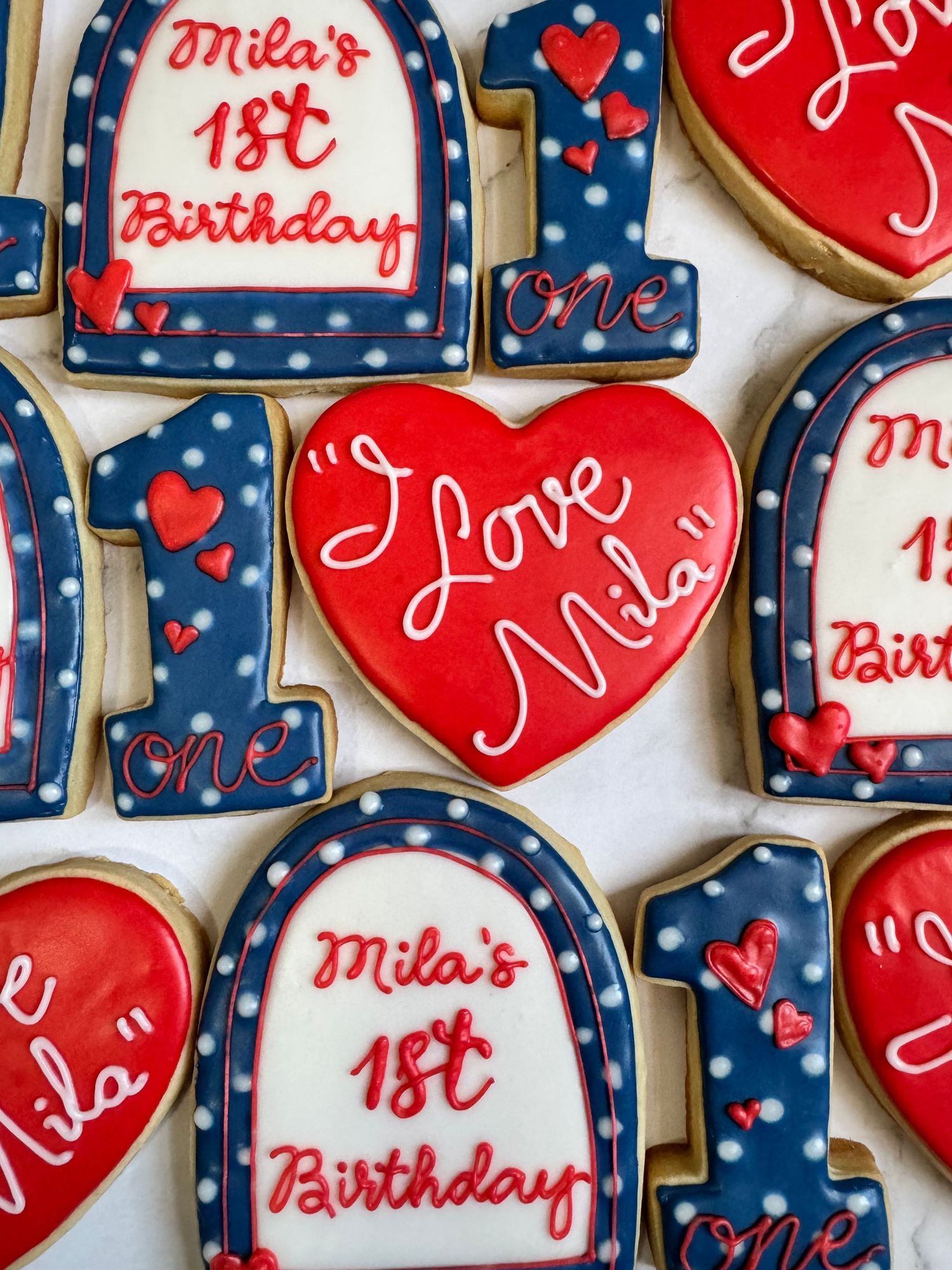 Red and navy blue decorated cookies with hearts and polka dots for a birthday celebration.