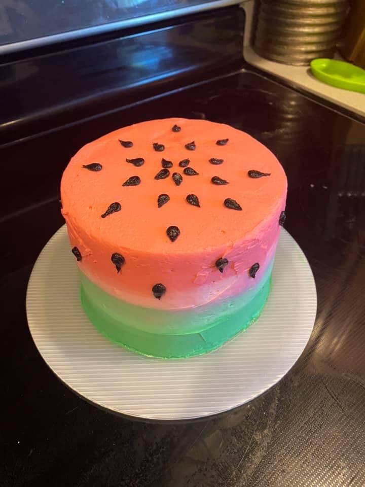 Watermelon-inspired cake with pink top, green bottom and black seed decorations.