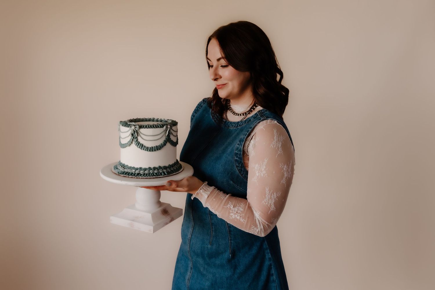Multiple views of someone holding a white cake with gray decorative details.