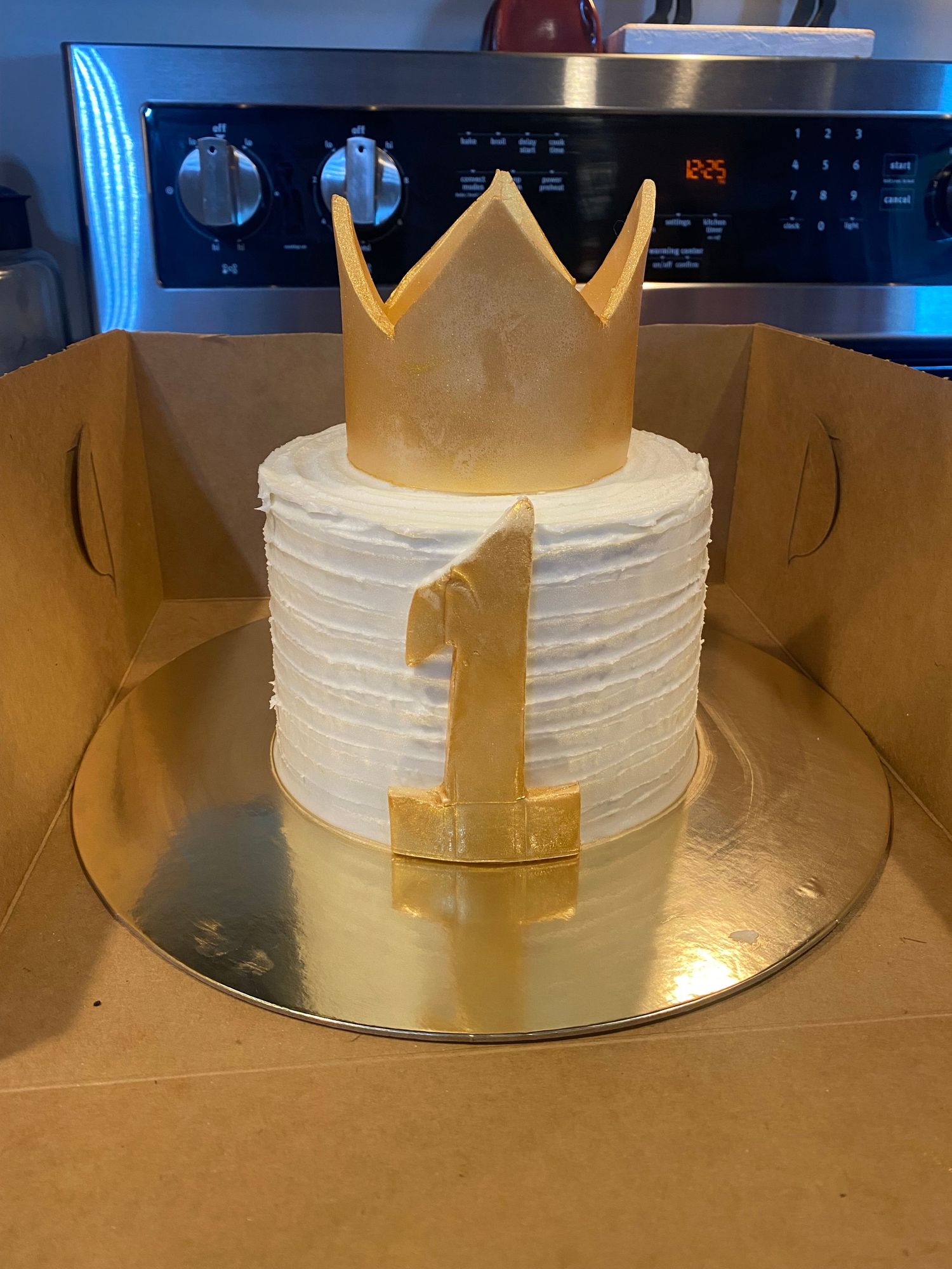 A white frosted cake decorated with a golden crown on top.