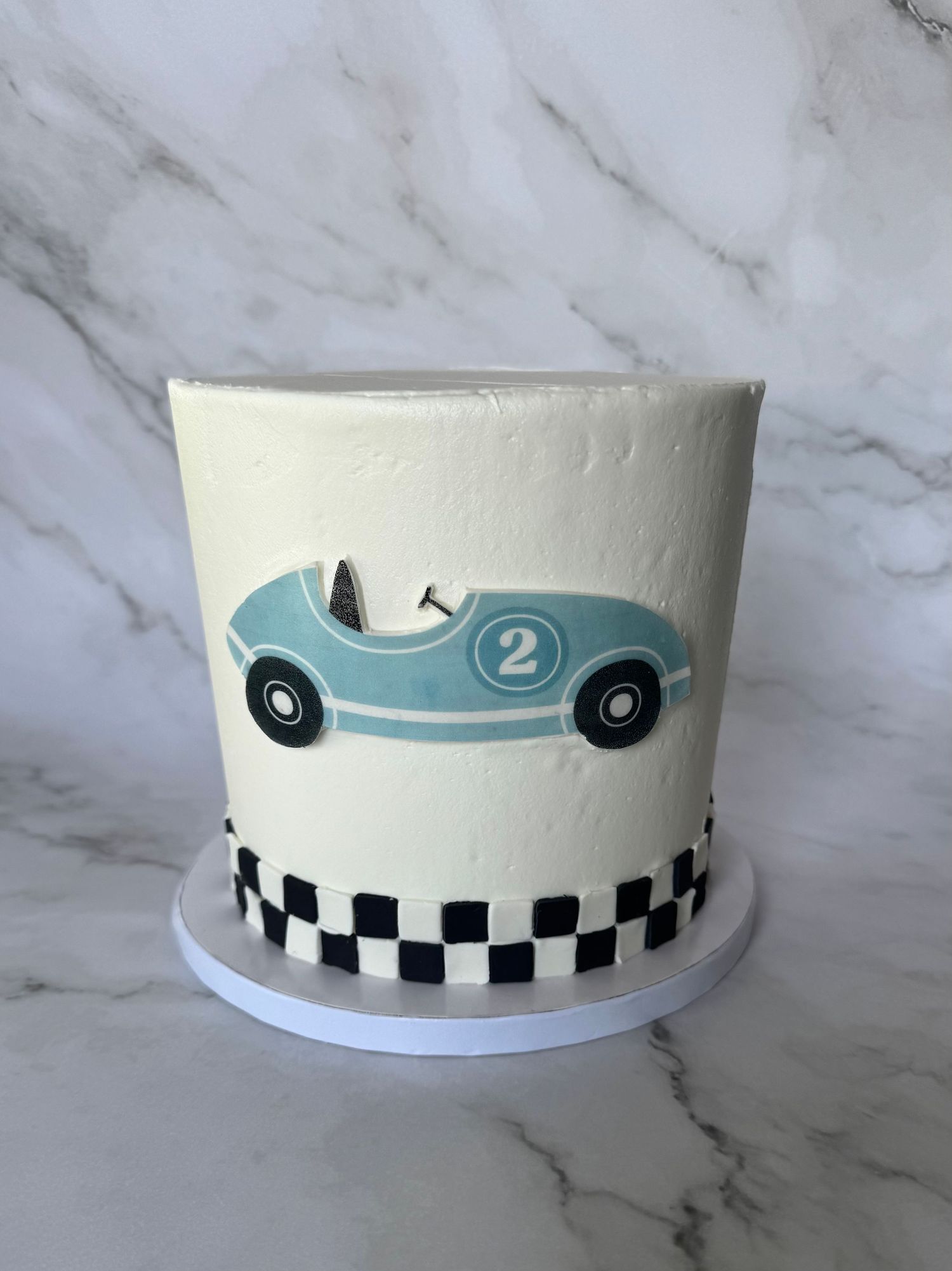 Racing car themed cake with vintage car design and checkered pattern in light blue and white.