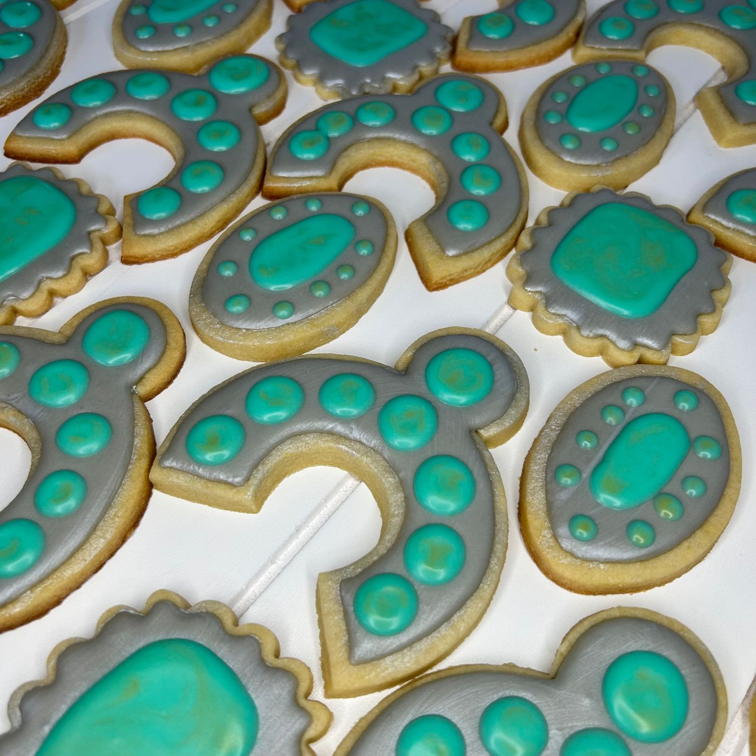 Teal colored heart-shaped sugar cookies with decorative dot patterns arranged in rows.