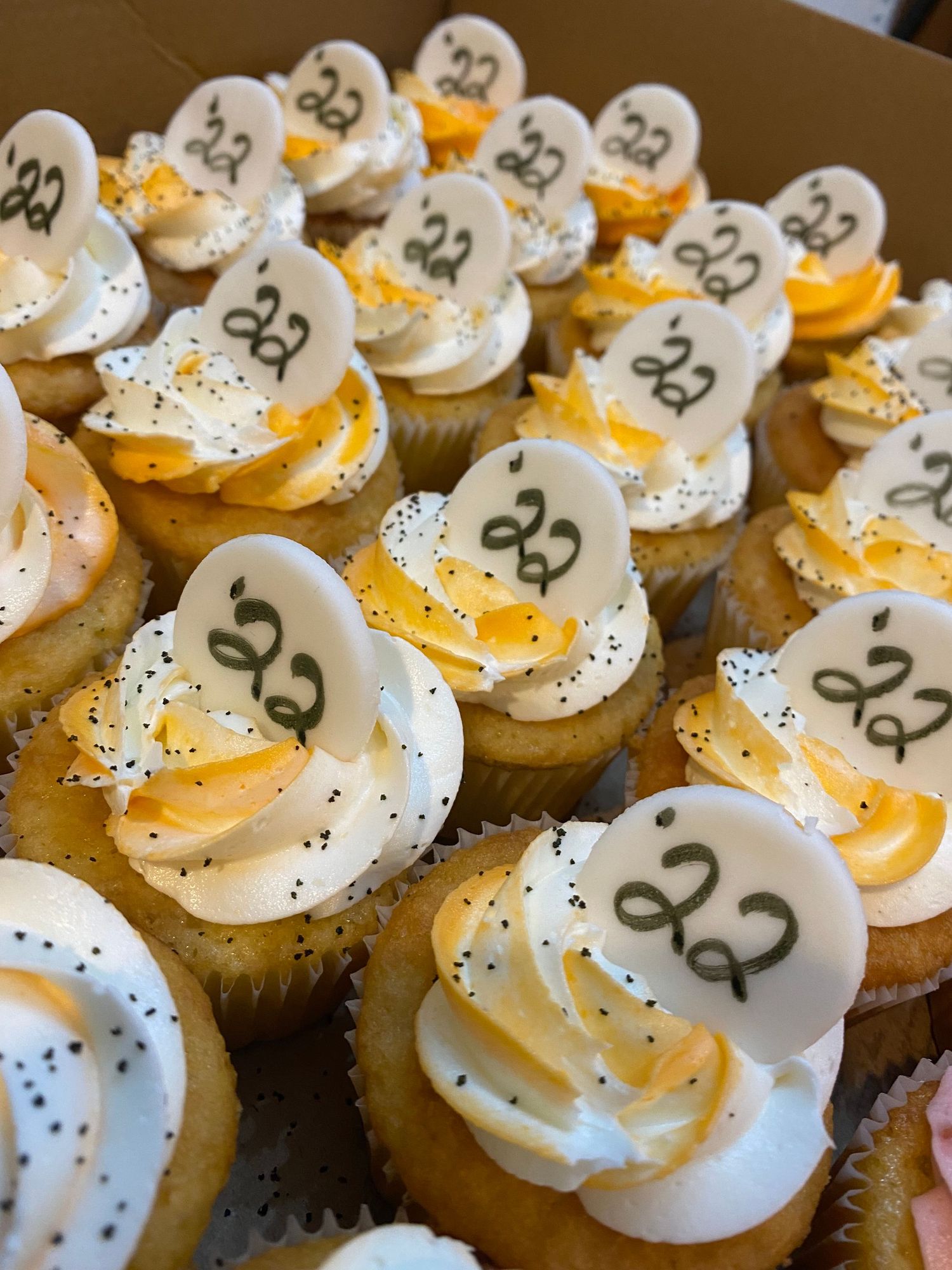 Vanilla cupcakes topped with white frosting and numbered decorations in black.