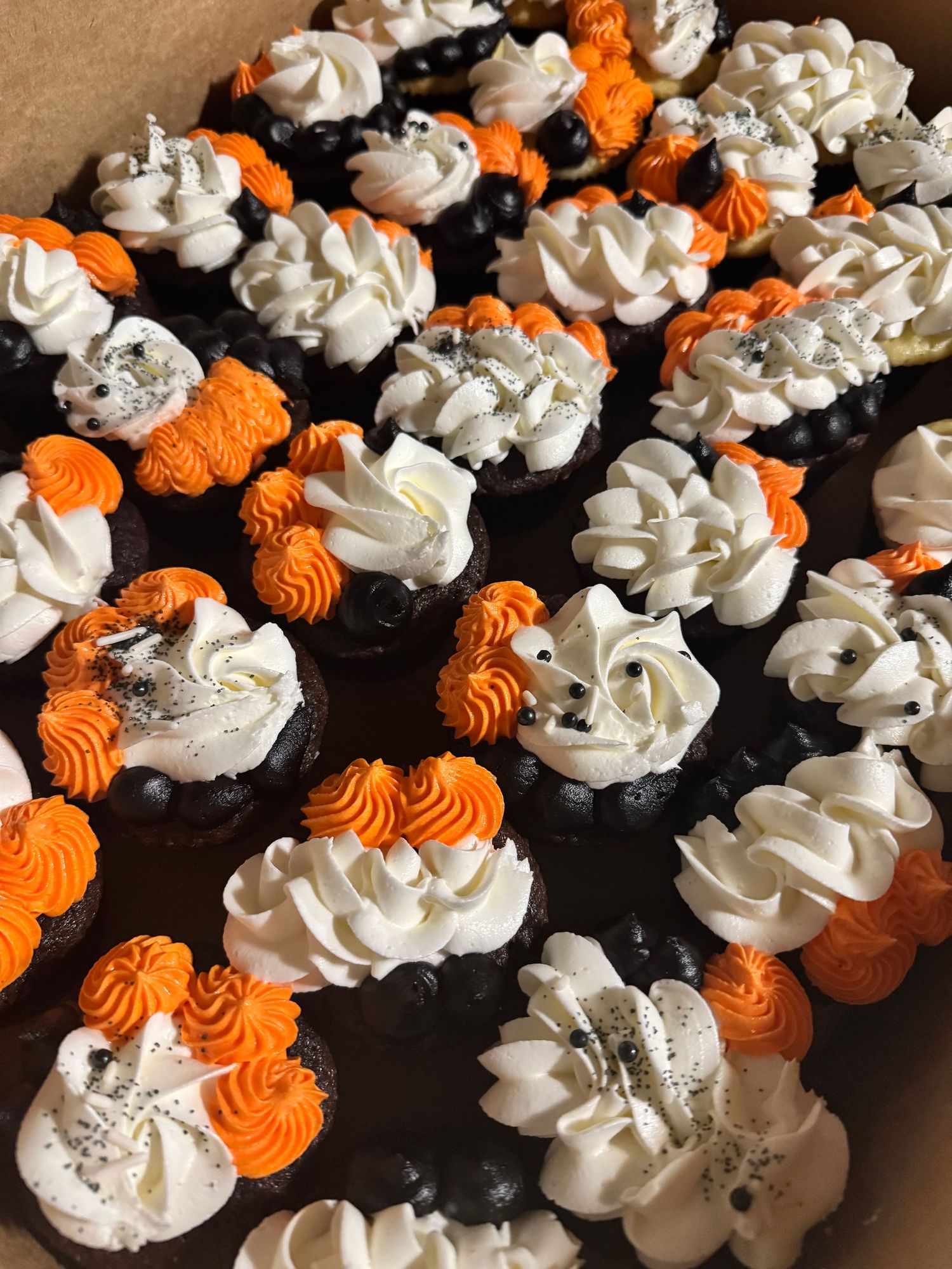 Halloween themed cupcakes with orange and white swirled frosting decorations.