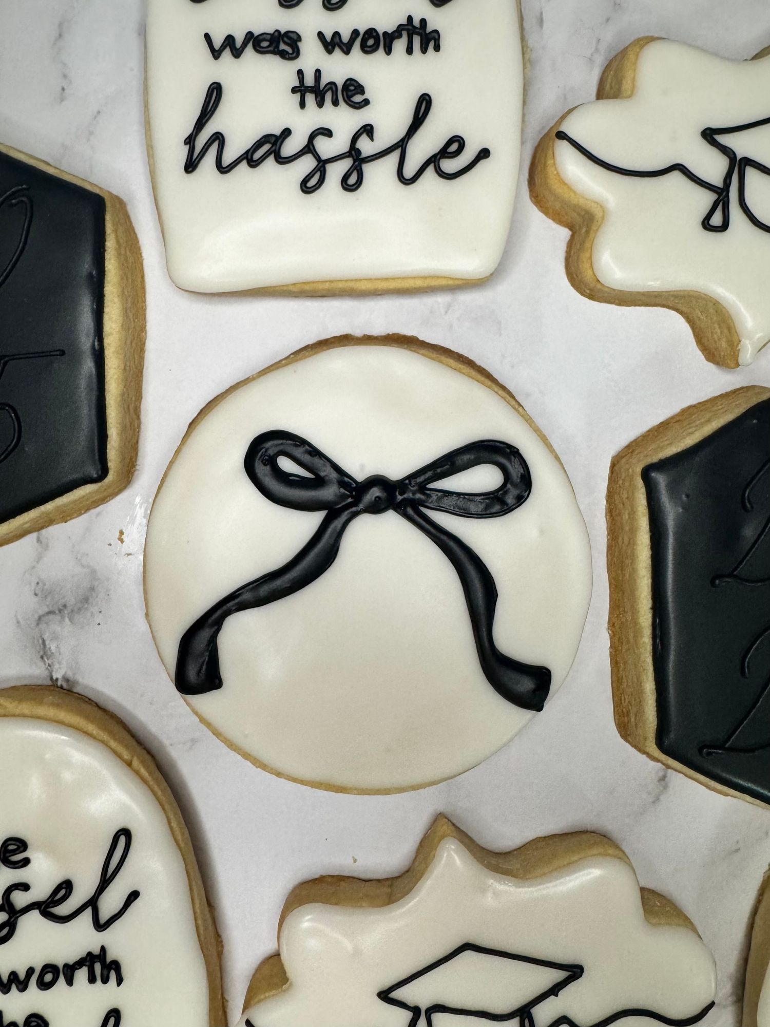 Elegant white sugar cookies decorated with black bows and graduation-themed designs.