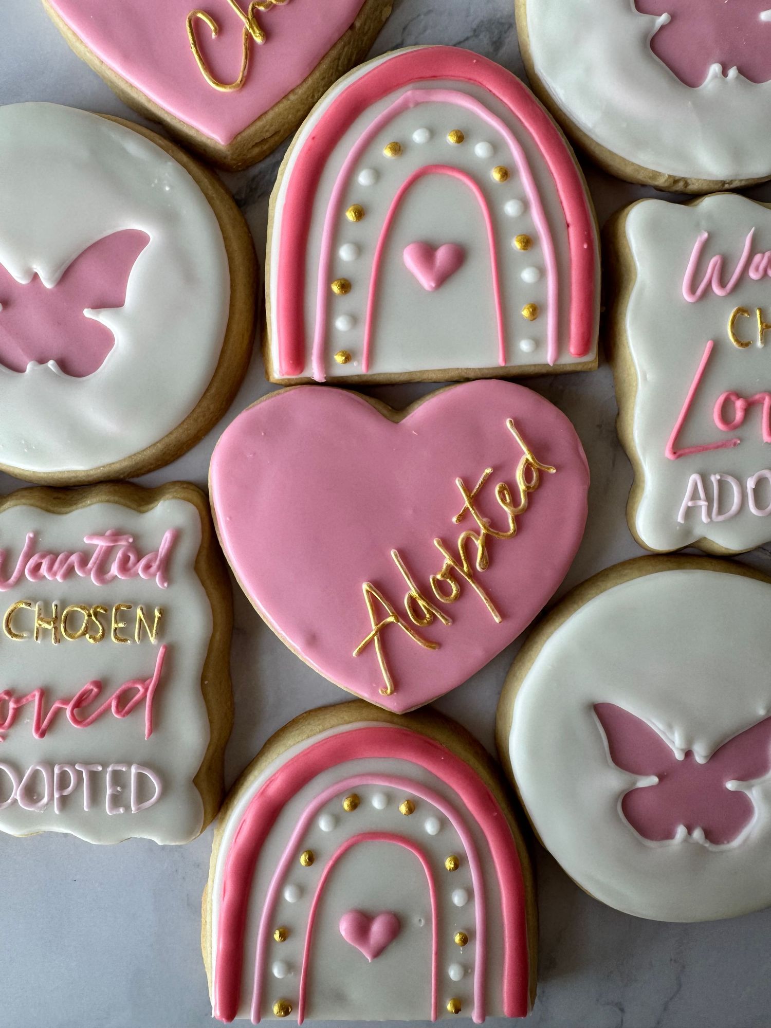 Pink and white frosted sugar cookies with delicate decorative details and text arranged in a pattern.