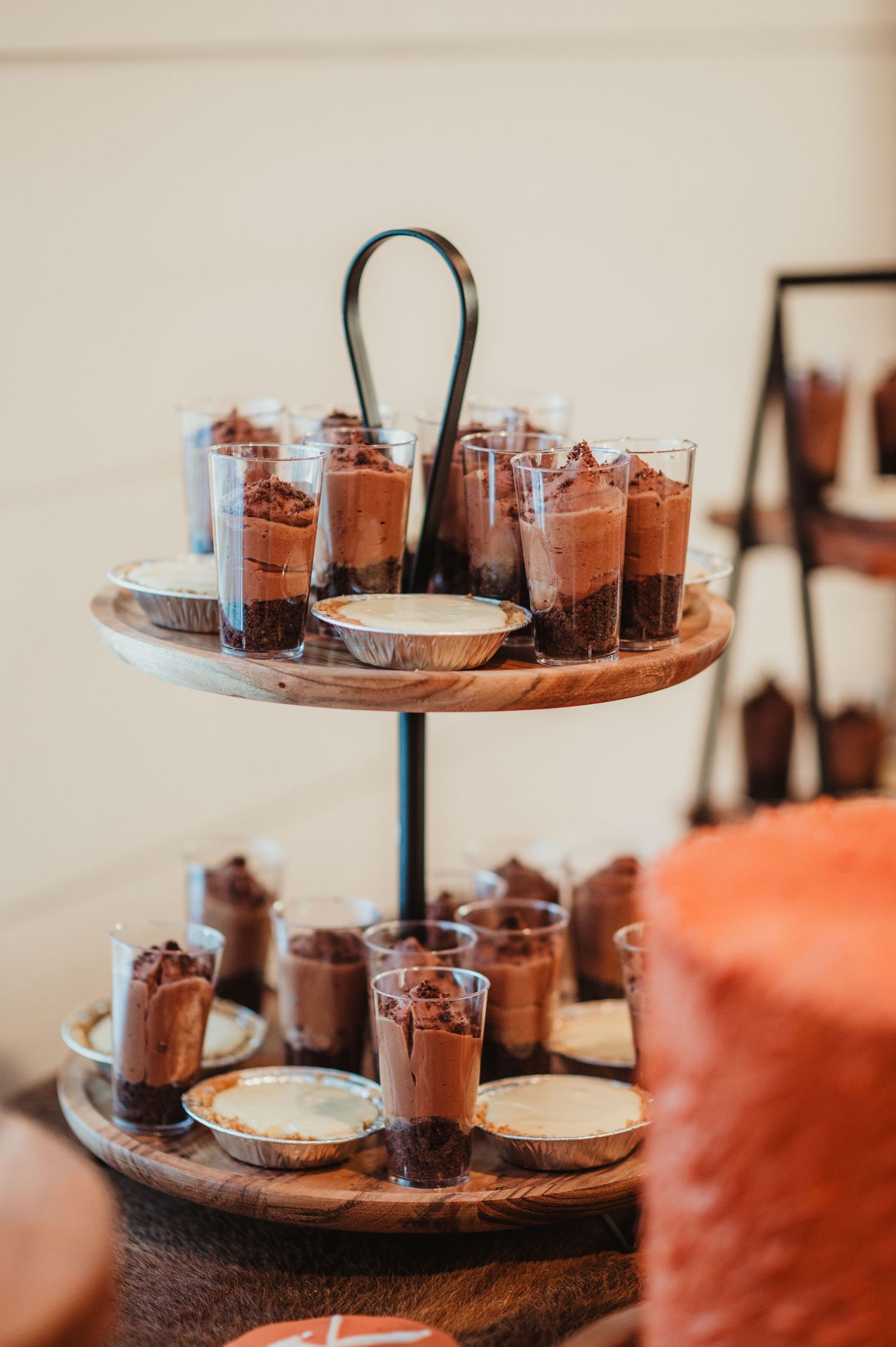 Two-tiered dessert stand filled with chocolate mousse cups on wooden surface.