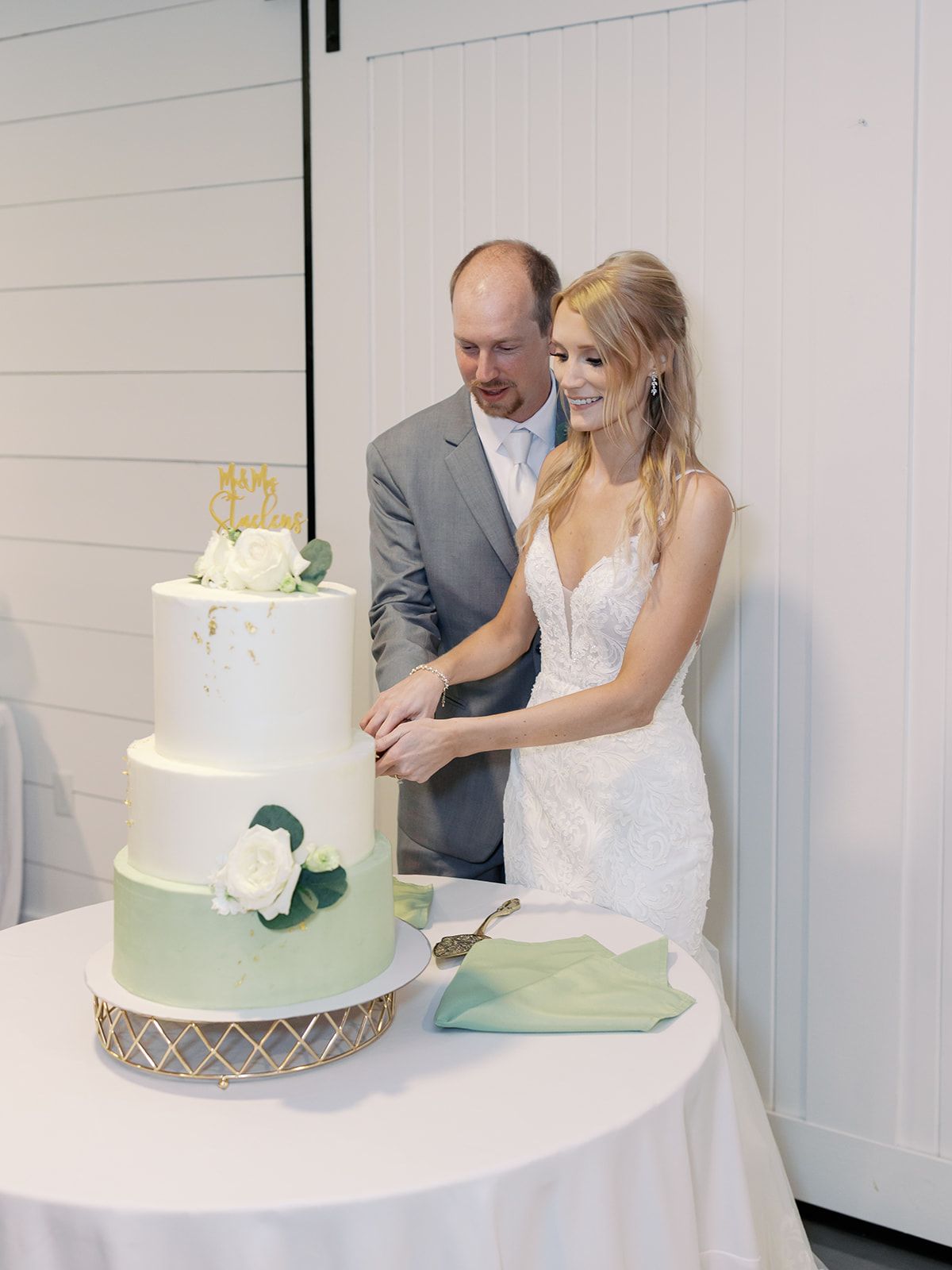 A white wedding cake being cut during a traditional cake cutting ceremony.