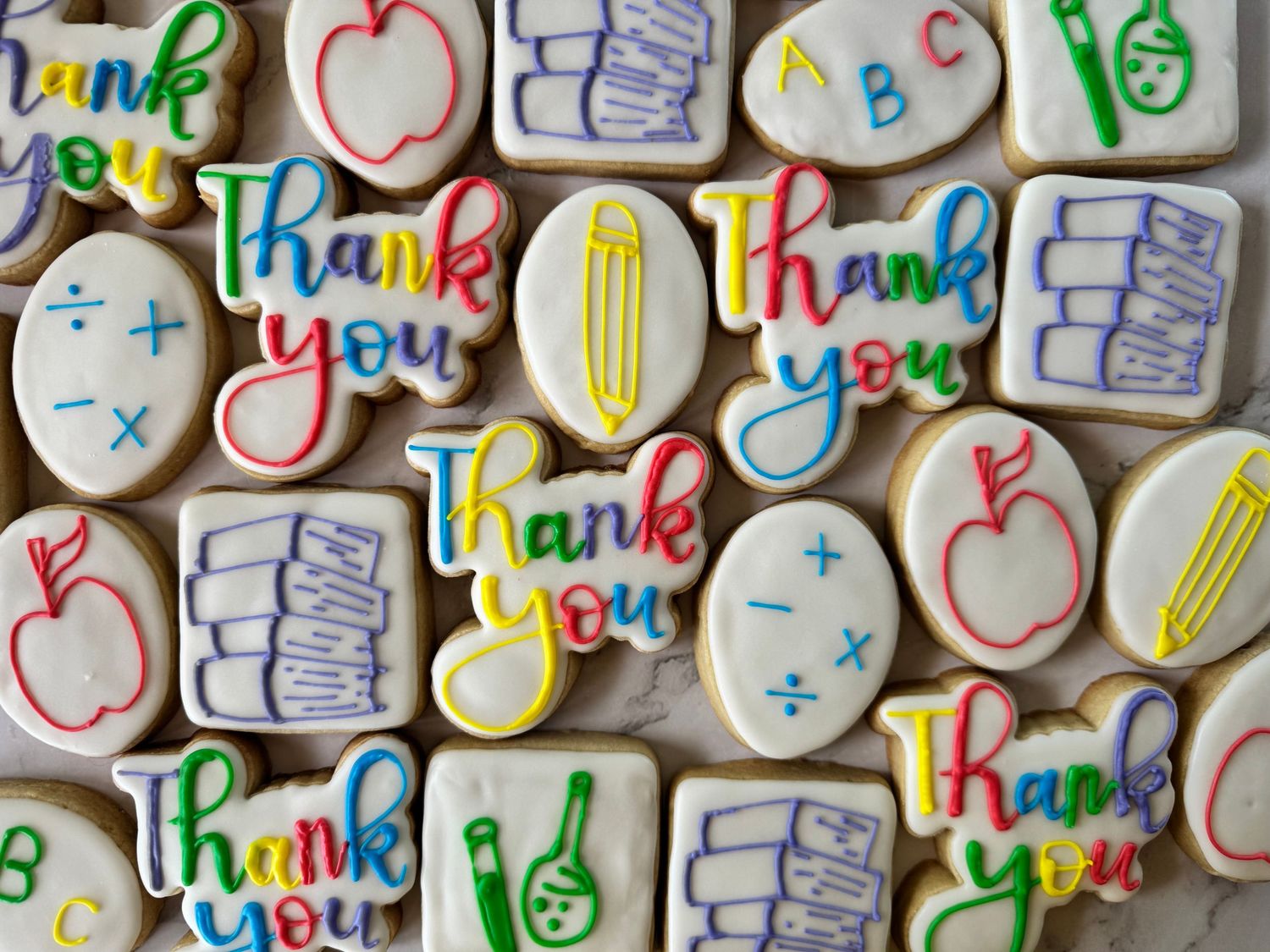 Colorful decorated sugar cookies with thank you messages and apple designs.