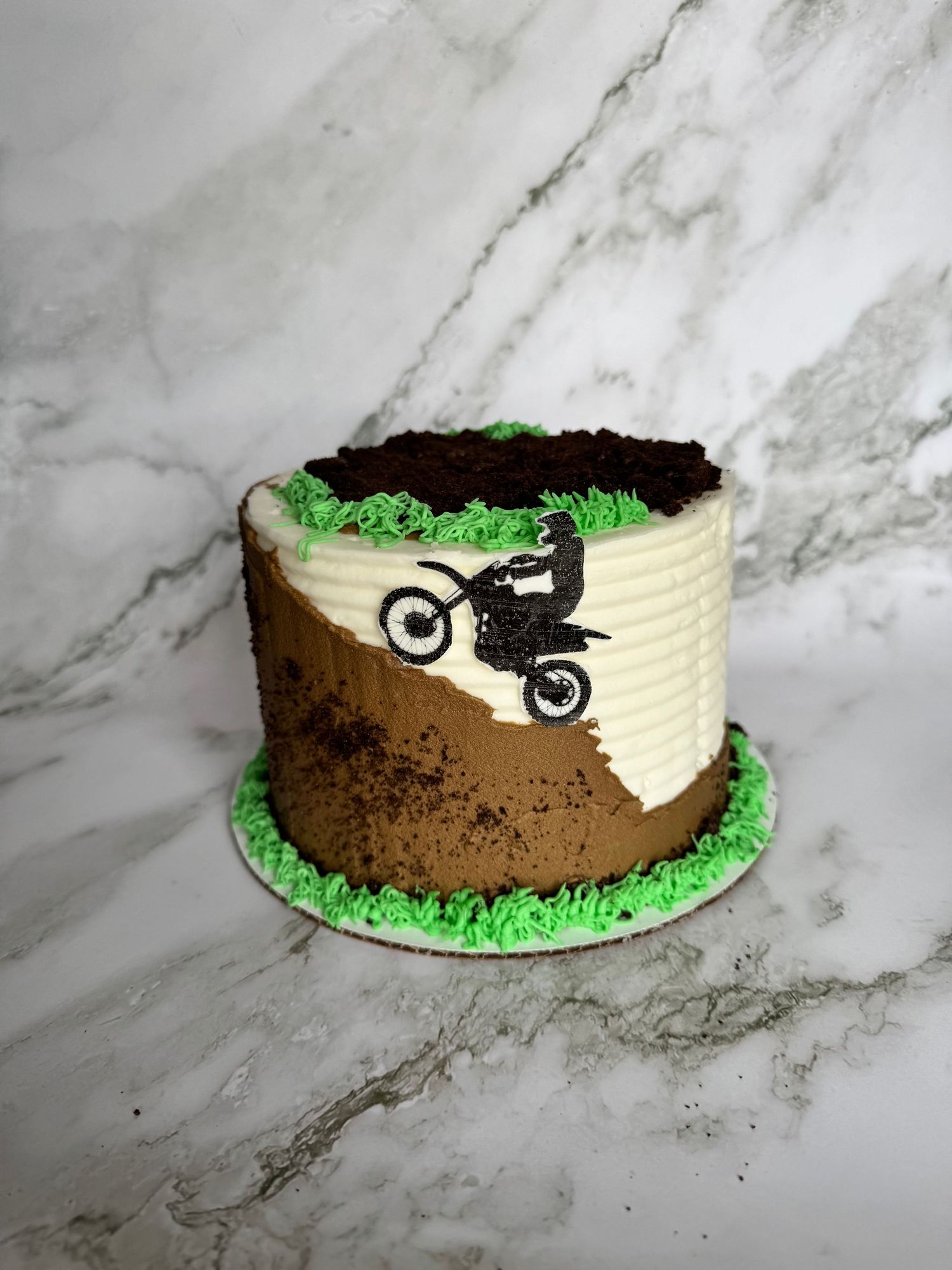Dirt bike themed cake with brown dirt track design and black silhouette of motorcycle jumping.