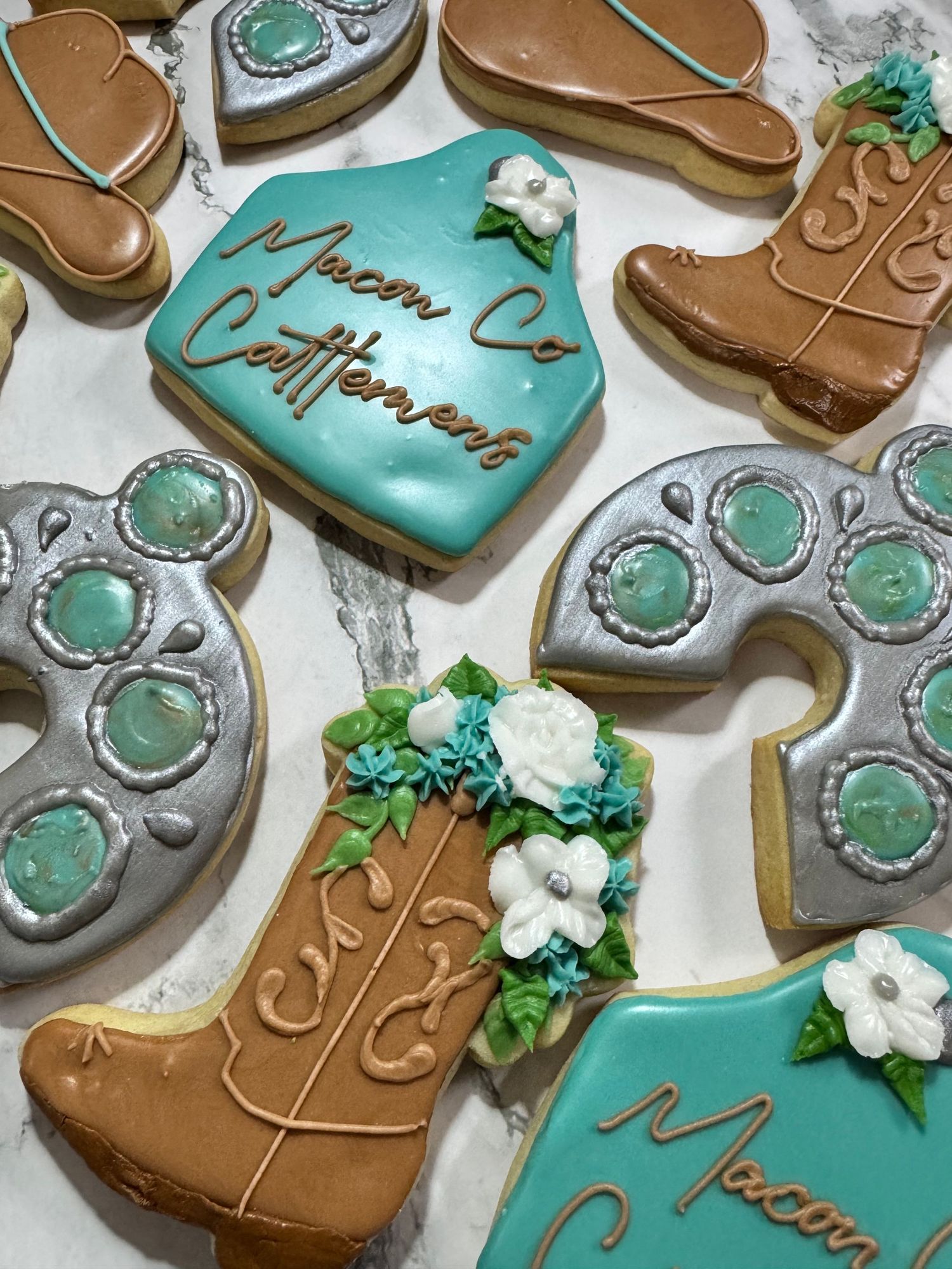 Decorative cookies with turquoise and brown designs featuring cowboy boots and rustic western patterns.