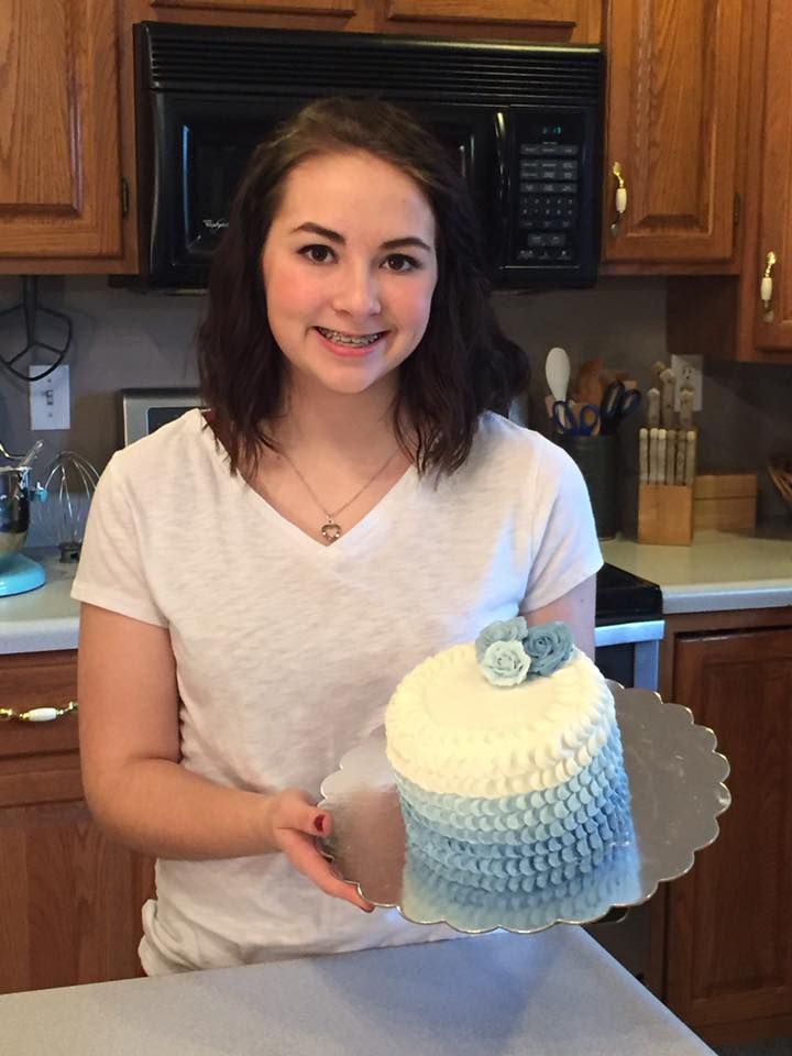 A beautifully decorated blue and white ombre cake displayed on a white stand.