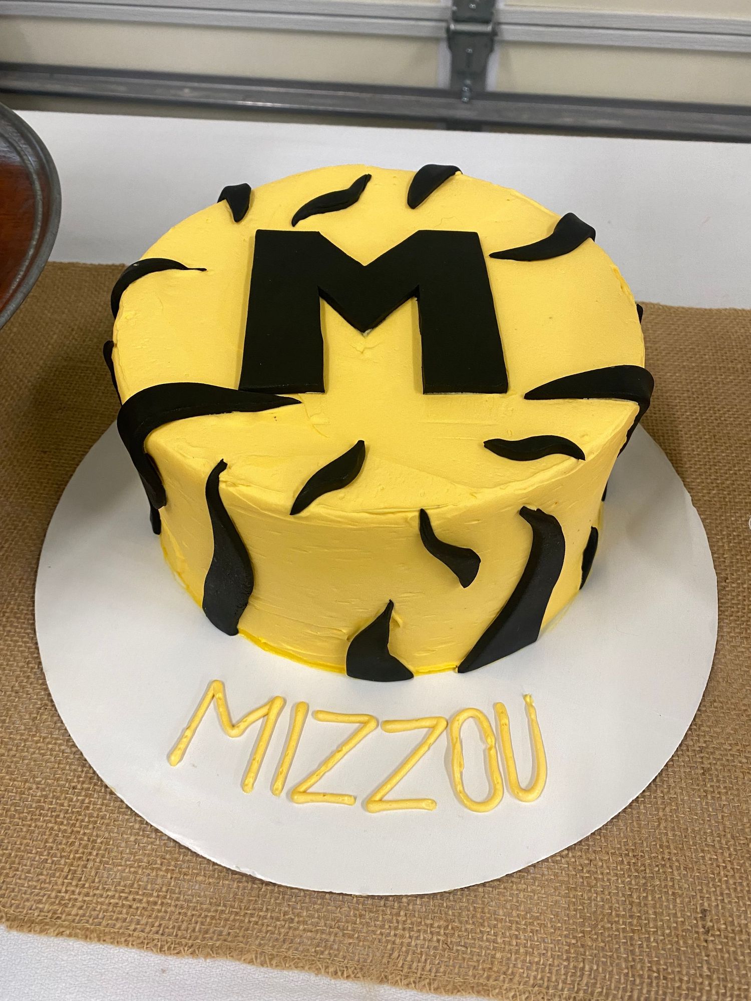 A yellow and black tiger stripe patterned cake with Mizzou written on the base.
