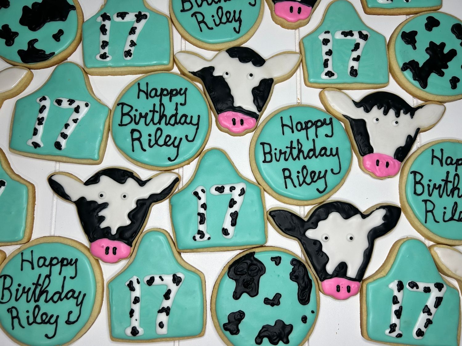 Turquoise colored sugar cookies featuring cow and farm animal designs.