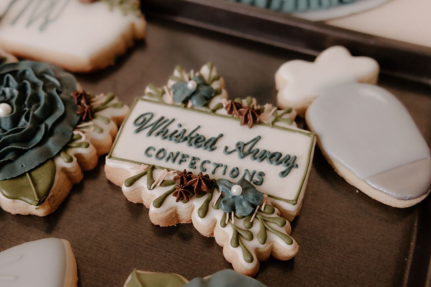 Close-up of intricately decorated wedding cookies with teal and white designs.