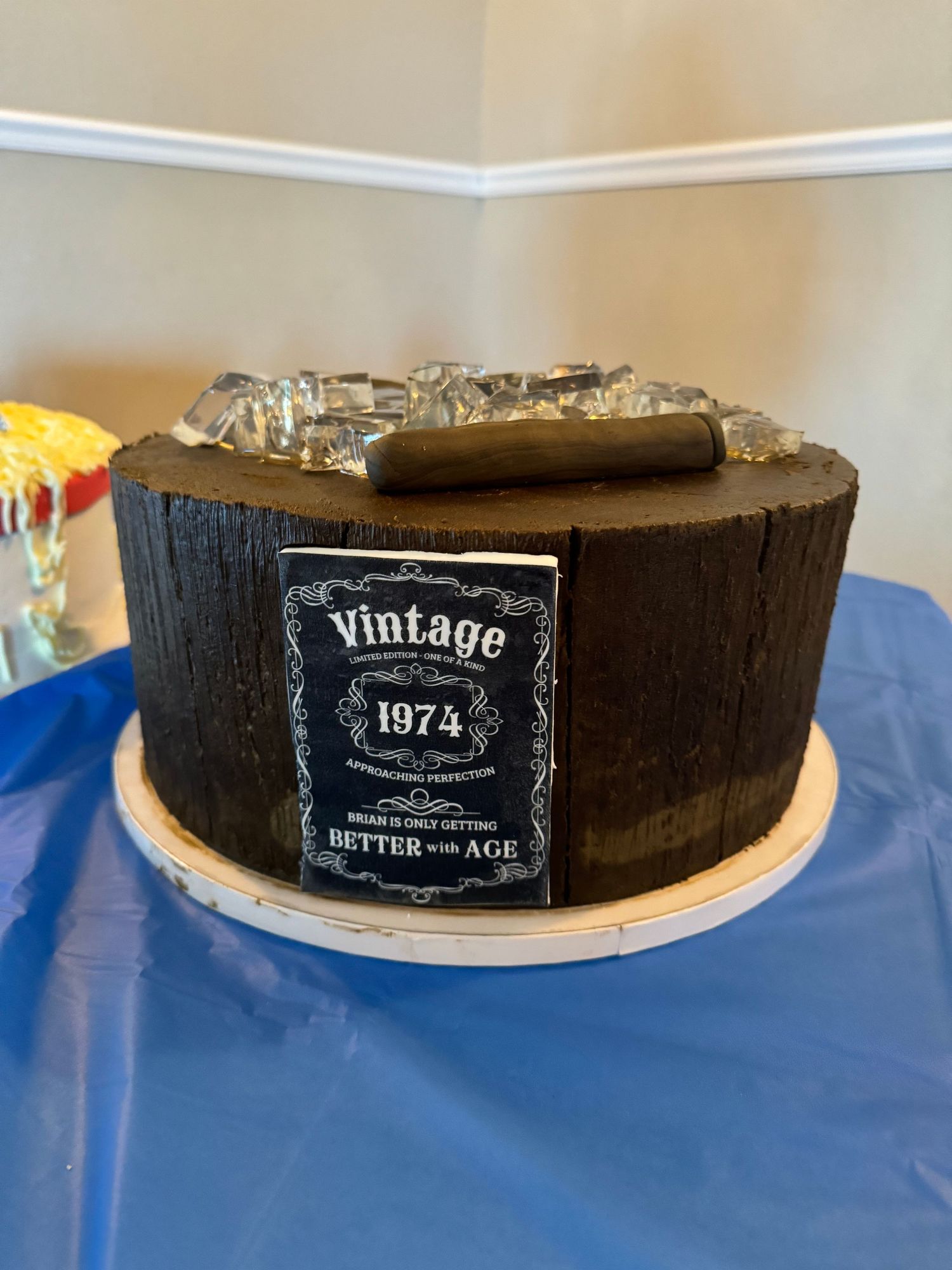A dark brown cake with a vintage 1974 label and silver decorative elements on top.