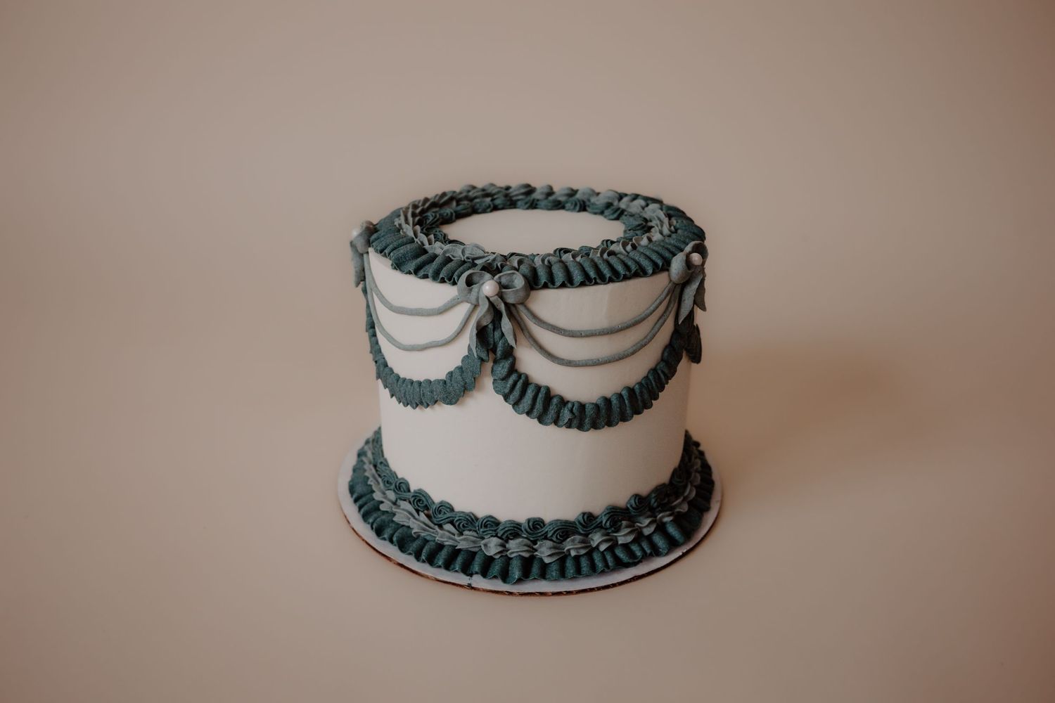 Classic white tiered cake decorated with teal ruffled accents and swags.