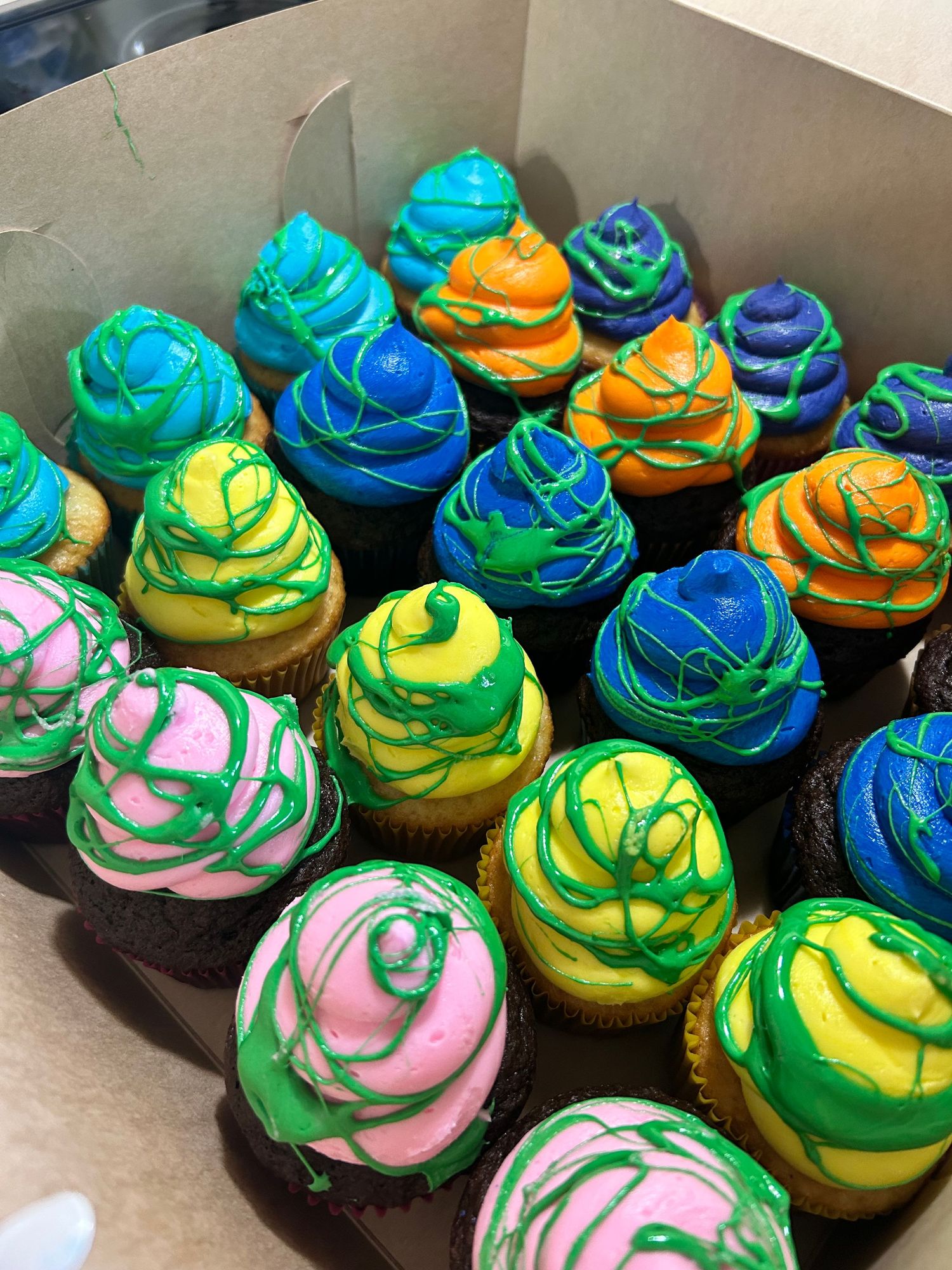 Colorful cupcakes with swirled blue, green, and pink frosting in tie-dye patterns.