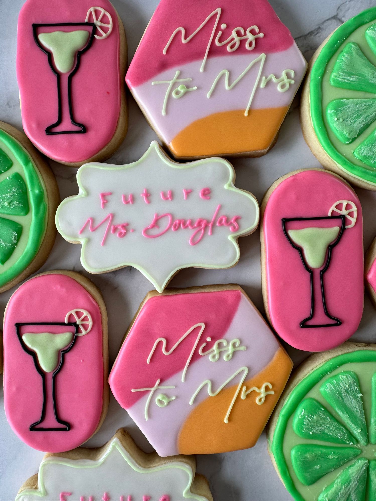 Bridal shower cookies decorated with pink and green icing featuring cocktail and text designs.