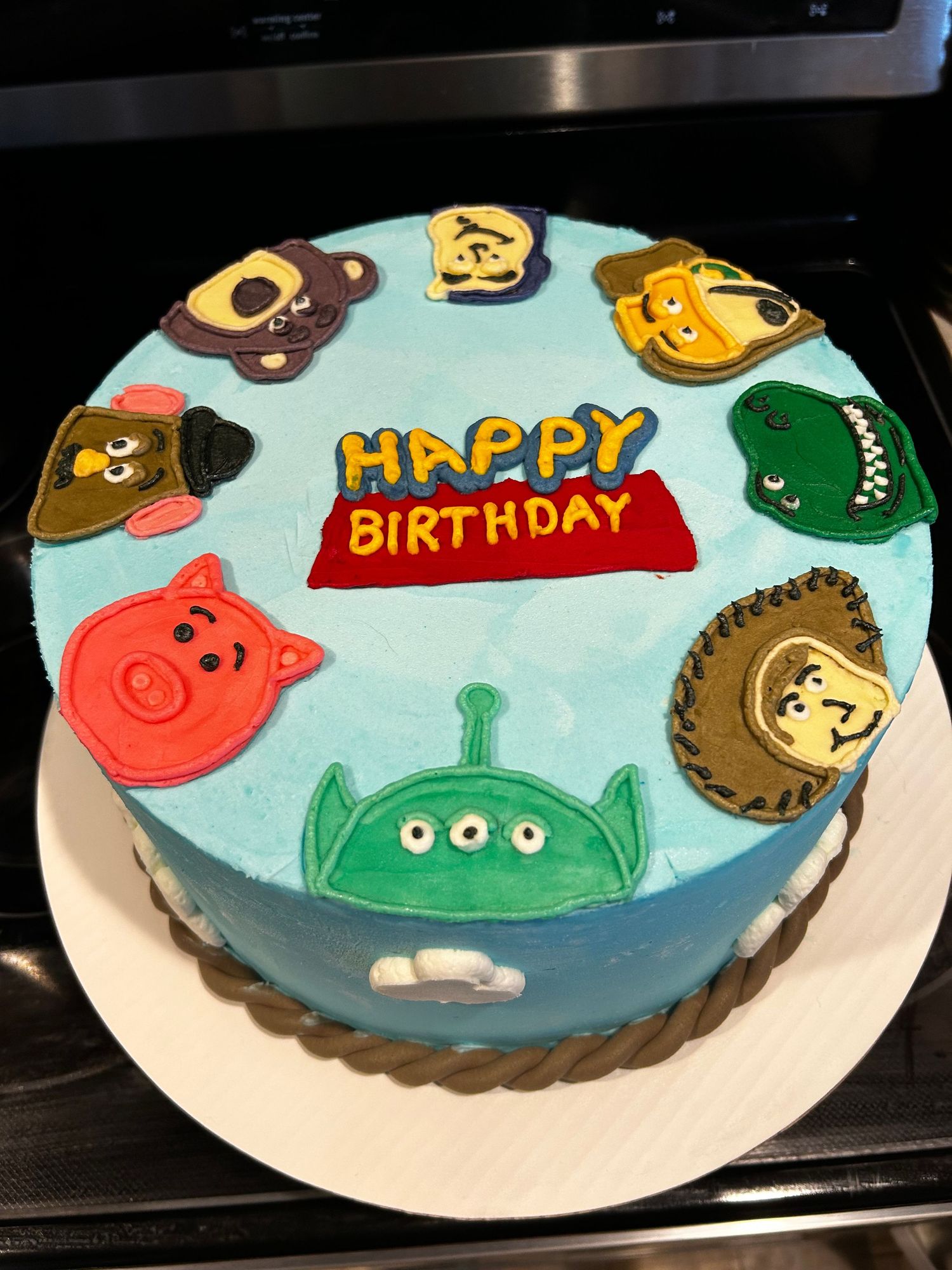 Children's birthday cake decorated with colorful cartoon animal faces on light blue fondant.