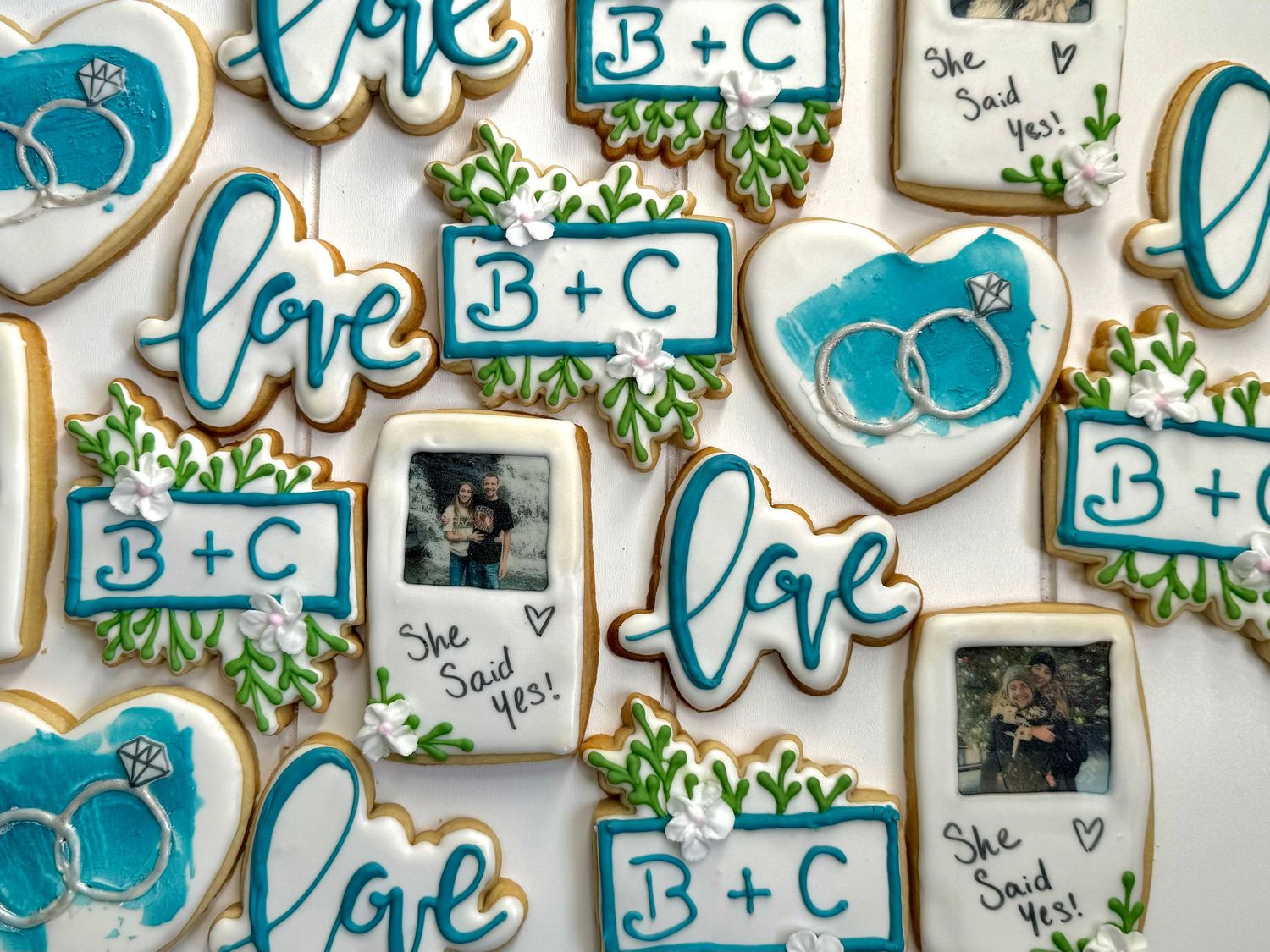 Blue and white wedding cookies featuring love text and monogram designs with floral accents.