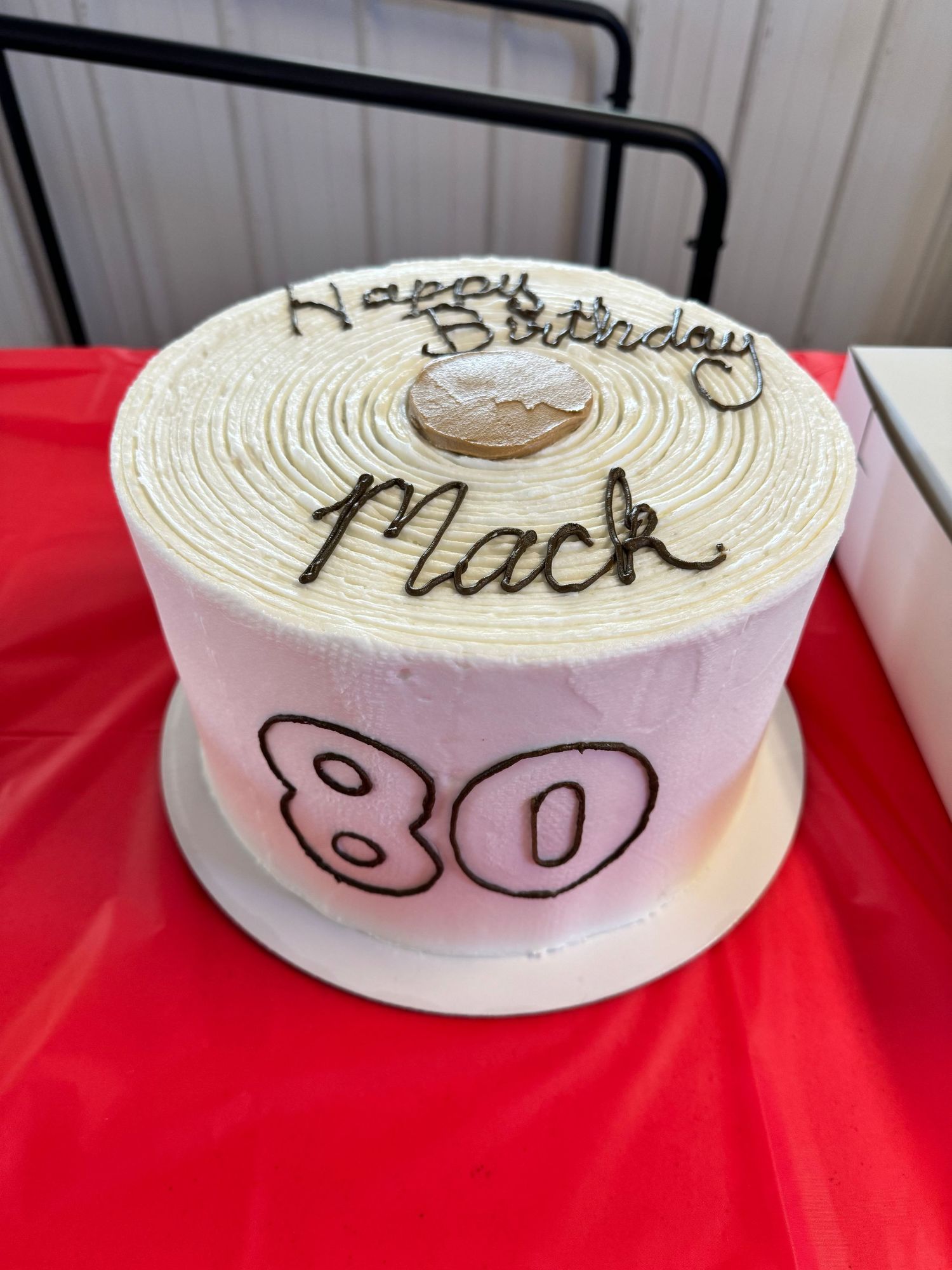 A white textured cake with the number 80 in pink and decorative writing on top.