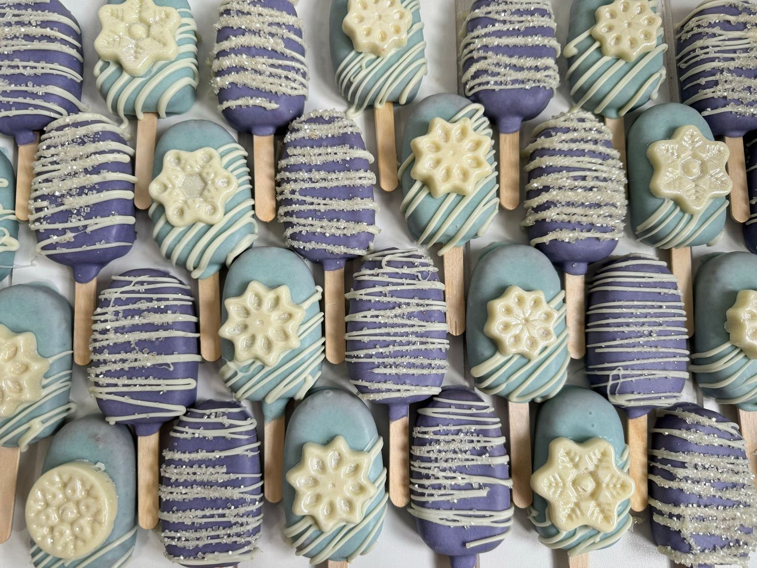 Winter-themed chocolate covered Oreos decorated with snowflakes in blue and silver.