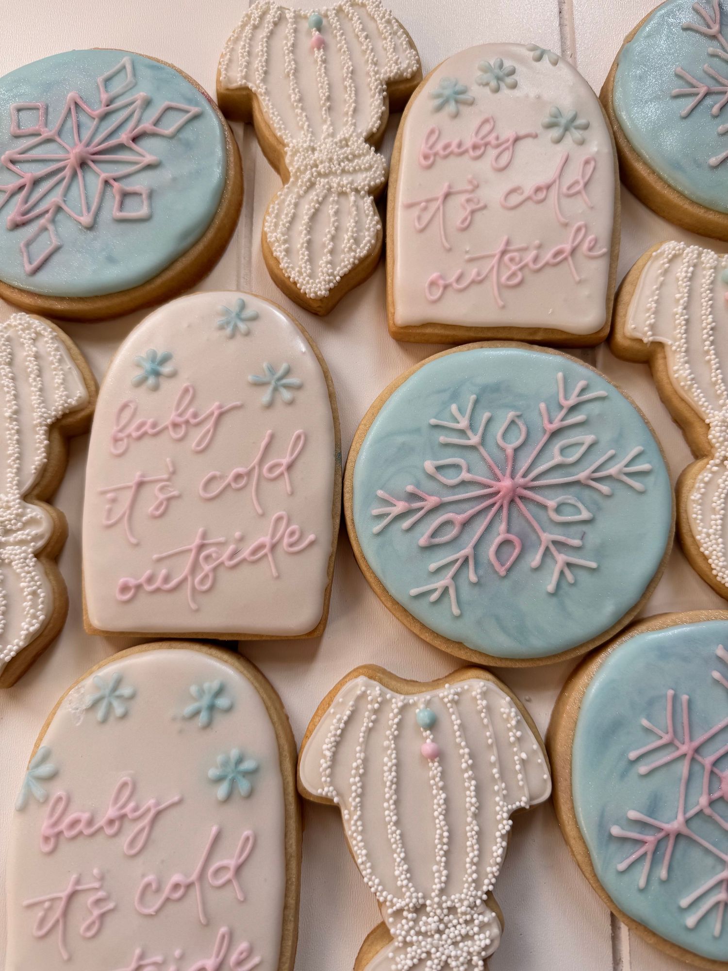 Winter themed sugar cookies with snowflakes and winter hats decorated in blue and white icing.
