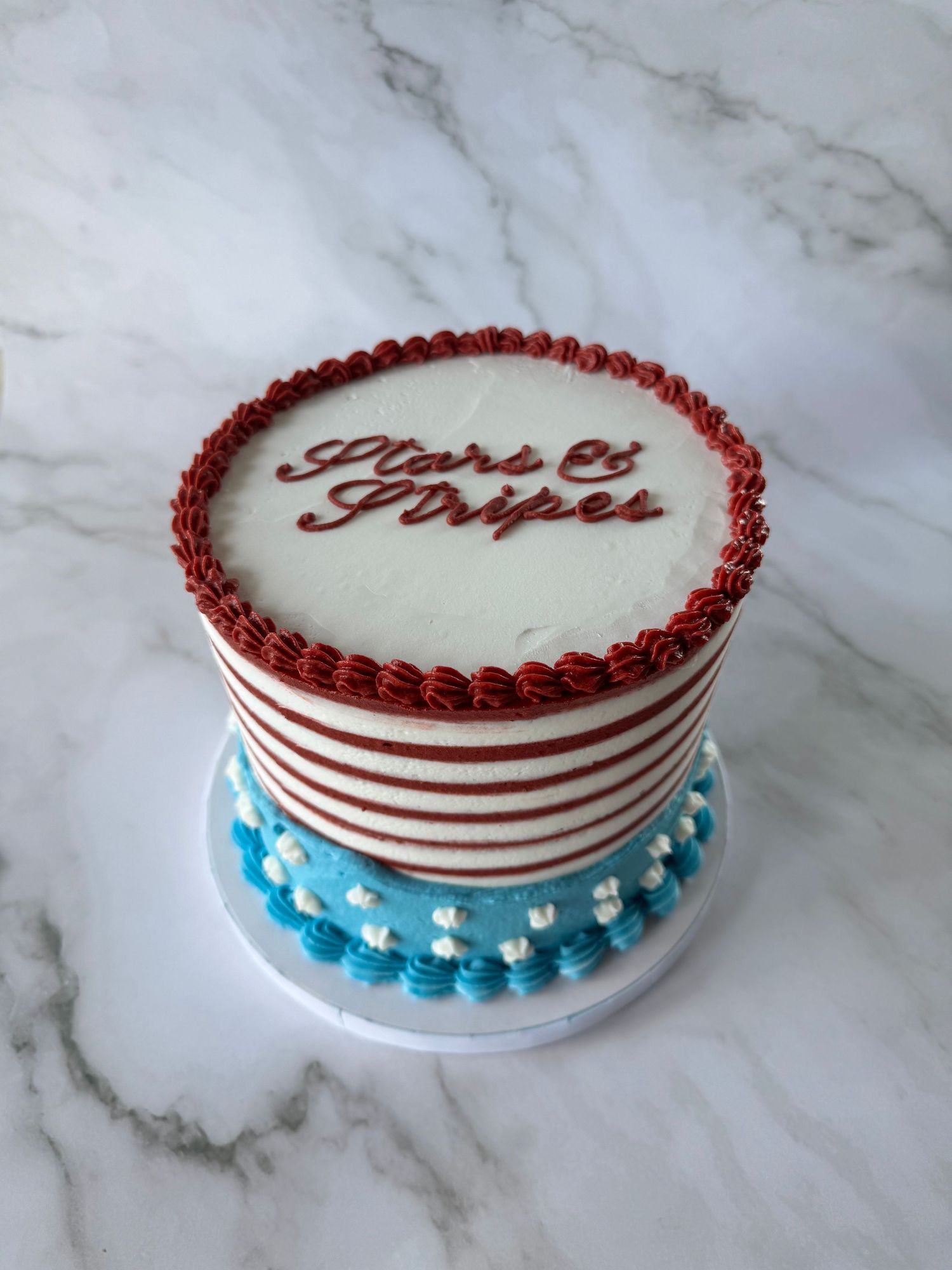 White cake with red and blue piped border decorations in a classic design.