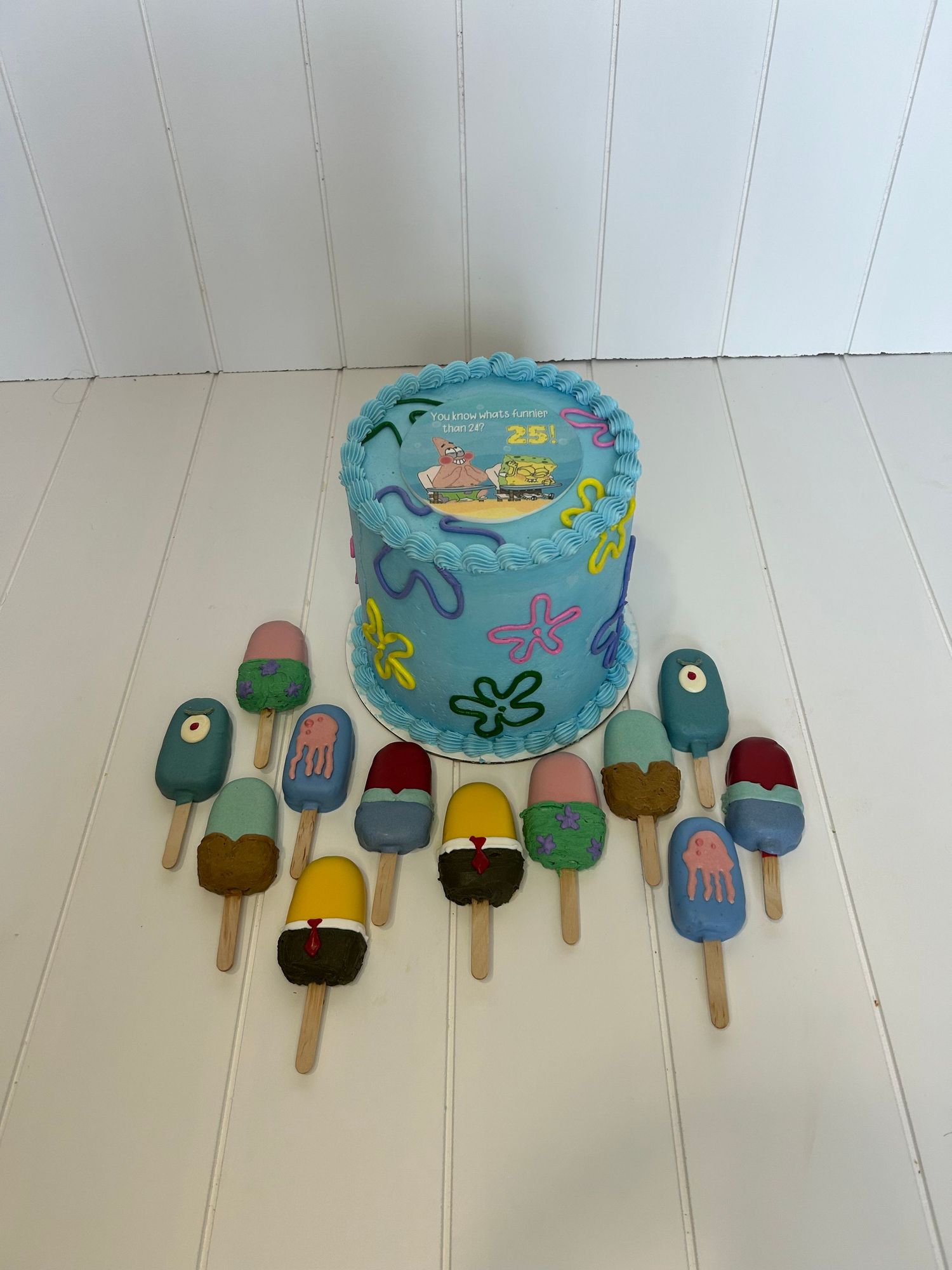 Blue ocean-themed cake surrounded by colorful cake pops designed to look like popsicles.