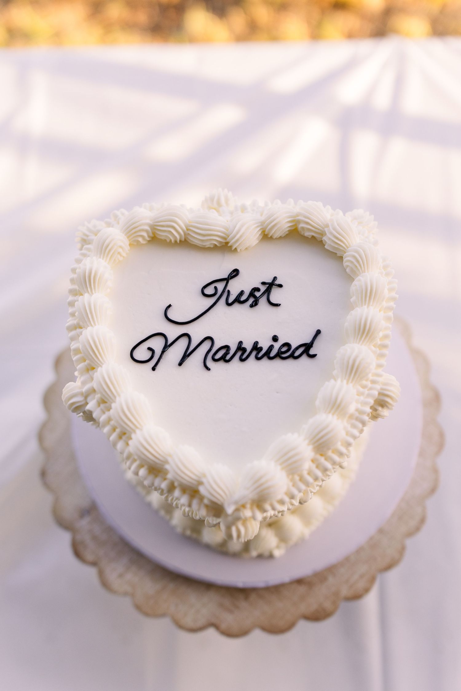 White heart-shaped wedding cookies with 'Just Married' text and decorative piped frosting borders.