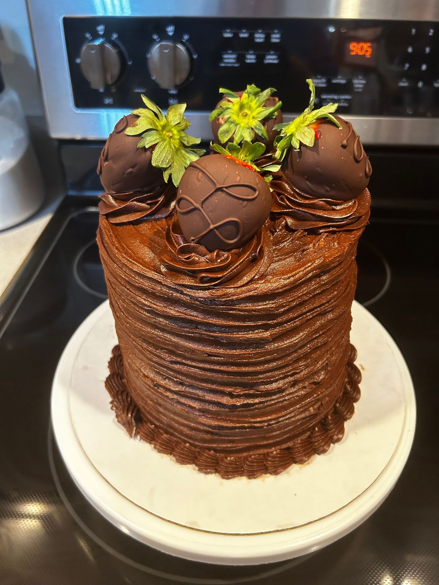 A chocolate cake with swirled frosting decoration and yellow flowers on top.