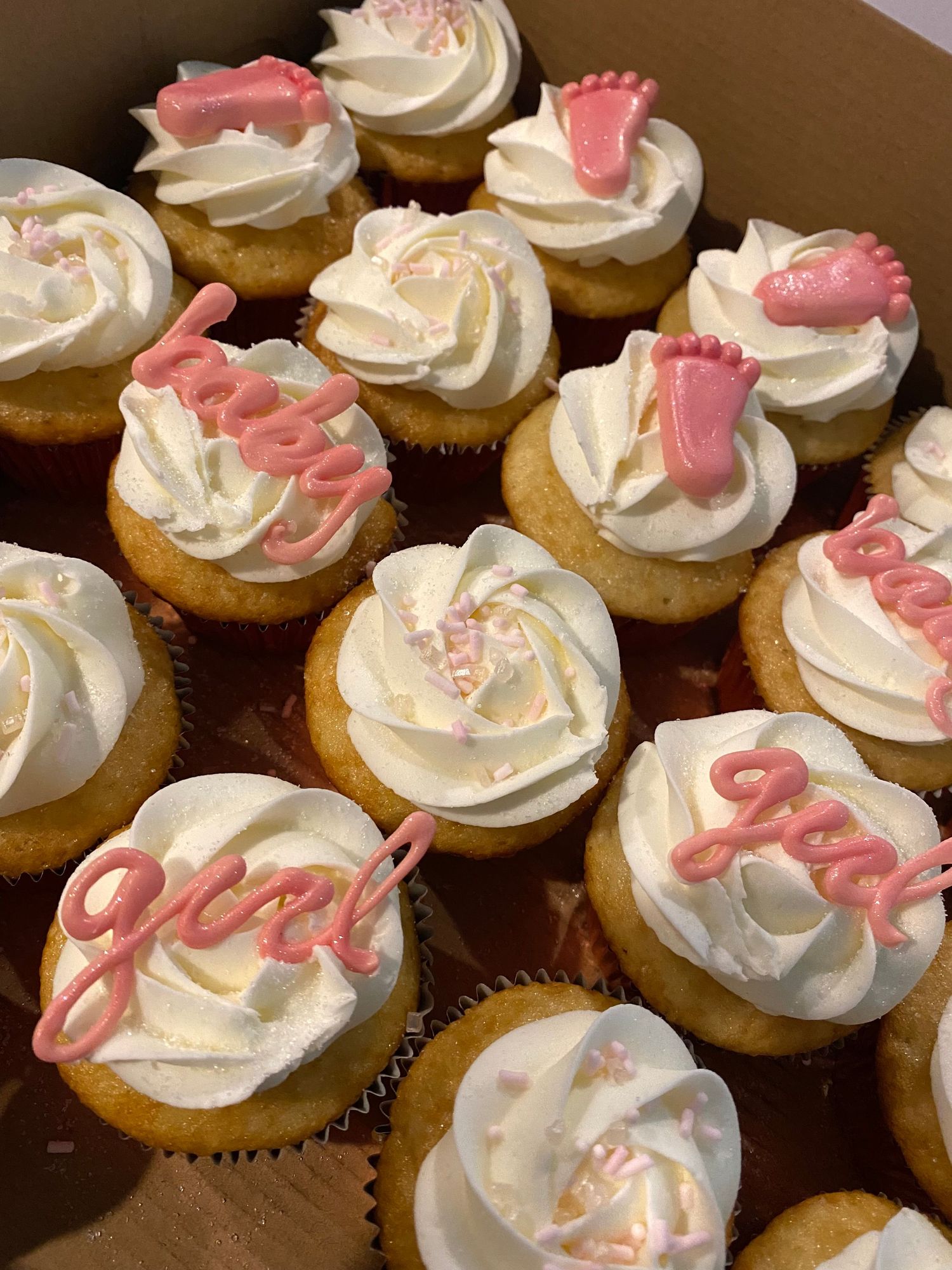Vanilla cupcakes decorated with white frosting and pink cursive writing on top.